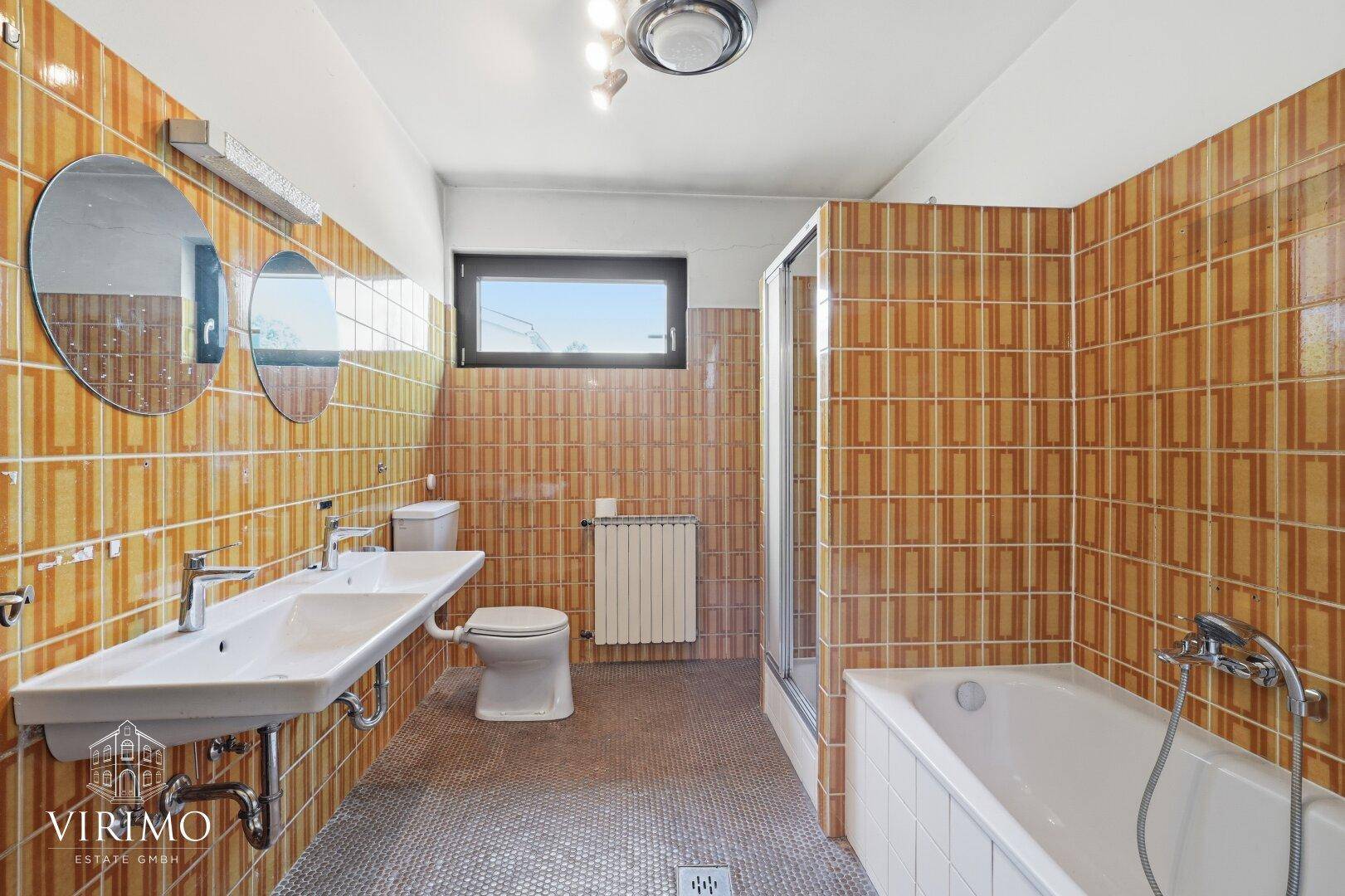 Badezimmer im 80er-Jahre-Stil mit Doppelwaschbecken, Badewanne und Dusche.