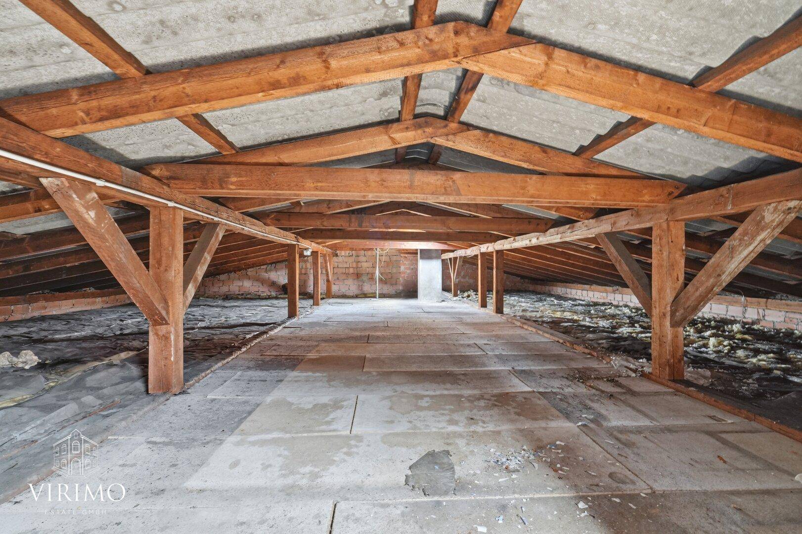 Großer, ungenutzter Dachboden mit Holzbalken und Betonboden, viel Potenzial.