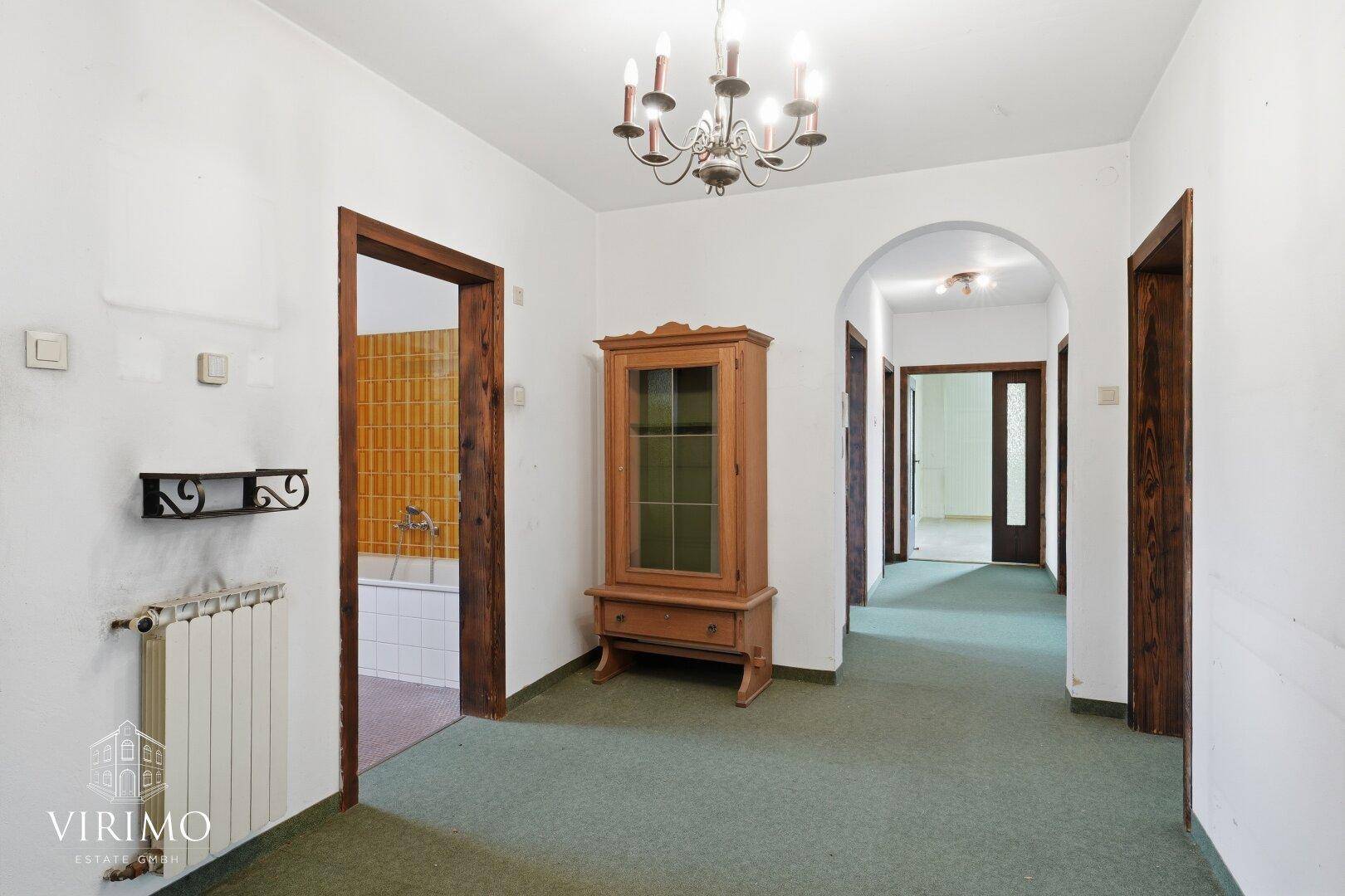 Geräumiger Flur mit Teppichboden, Holzschrank und Zugang zu weiteren Räumen.