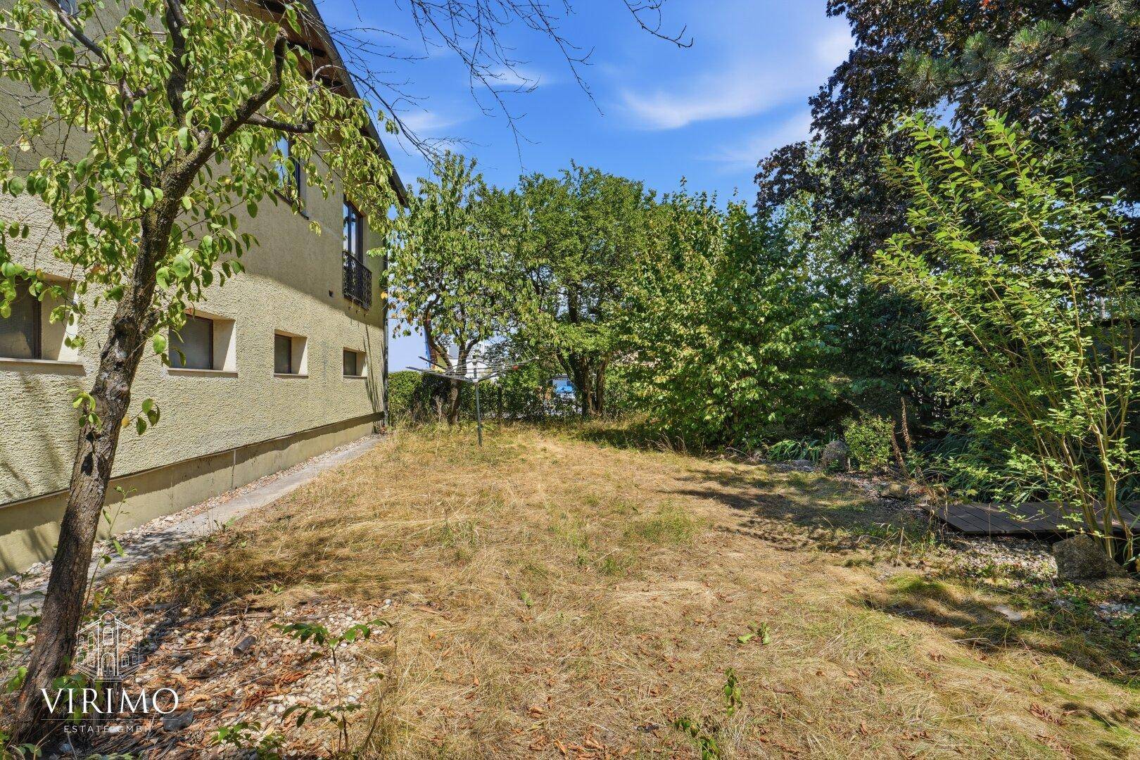 Großer Gartenbereich mit Rasen und Bäumen, ideal für Erholung im Freien.