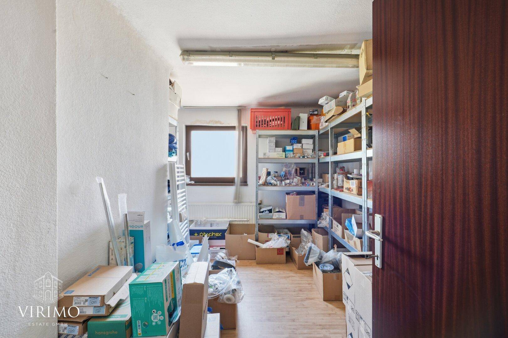 Lagerraum mit Regalen, Kartons und einem Fenster, gut organisiert.