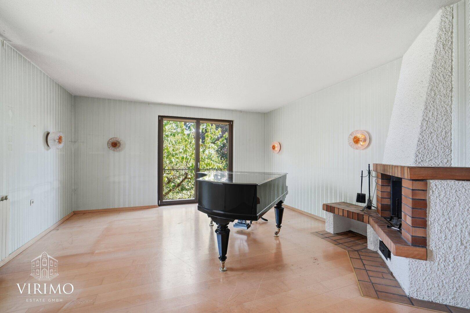 Helles Wohnzimmer mit Flügel, Kamin und Zugang zum Garten oder Balkon.
