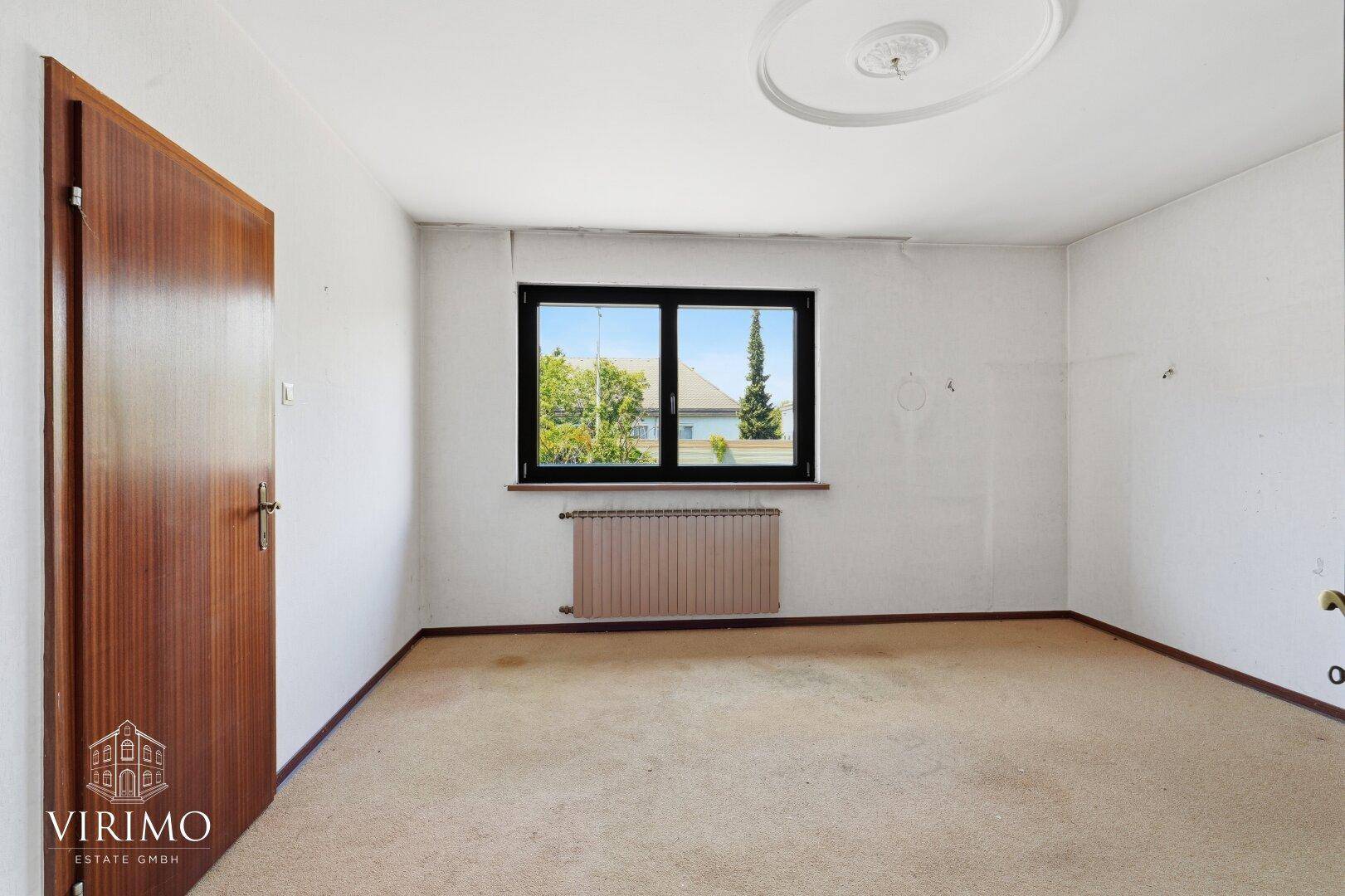 Raum mit Teppichboden, Fenster und Holztür, ideal für eine Neugestaltung.