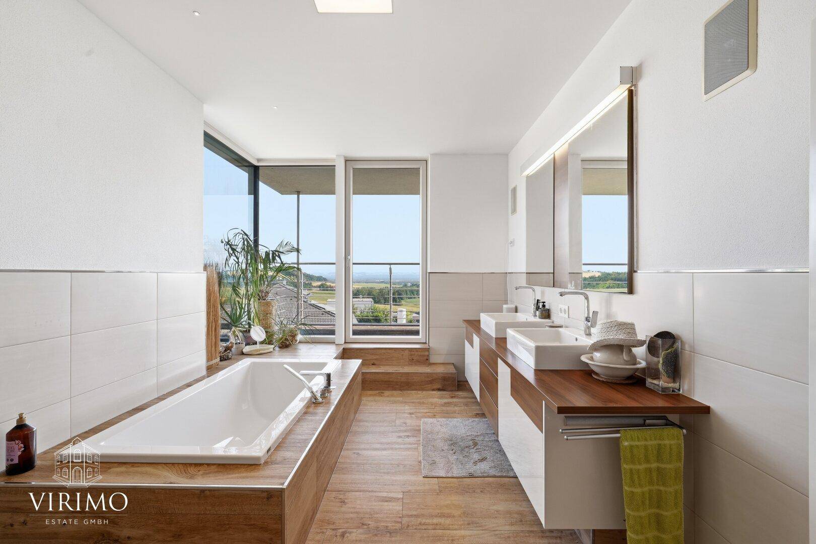 Modernes Badezimmer mit Doppelwaschbecken, Badewanne und großen Fenstern mit Ausblick.