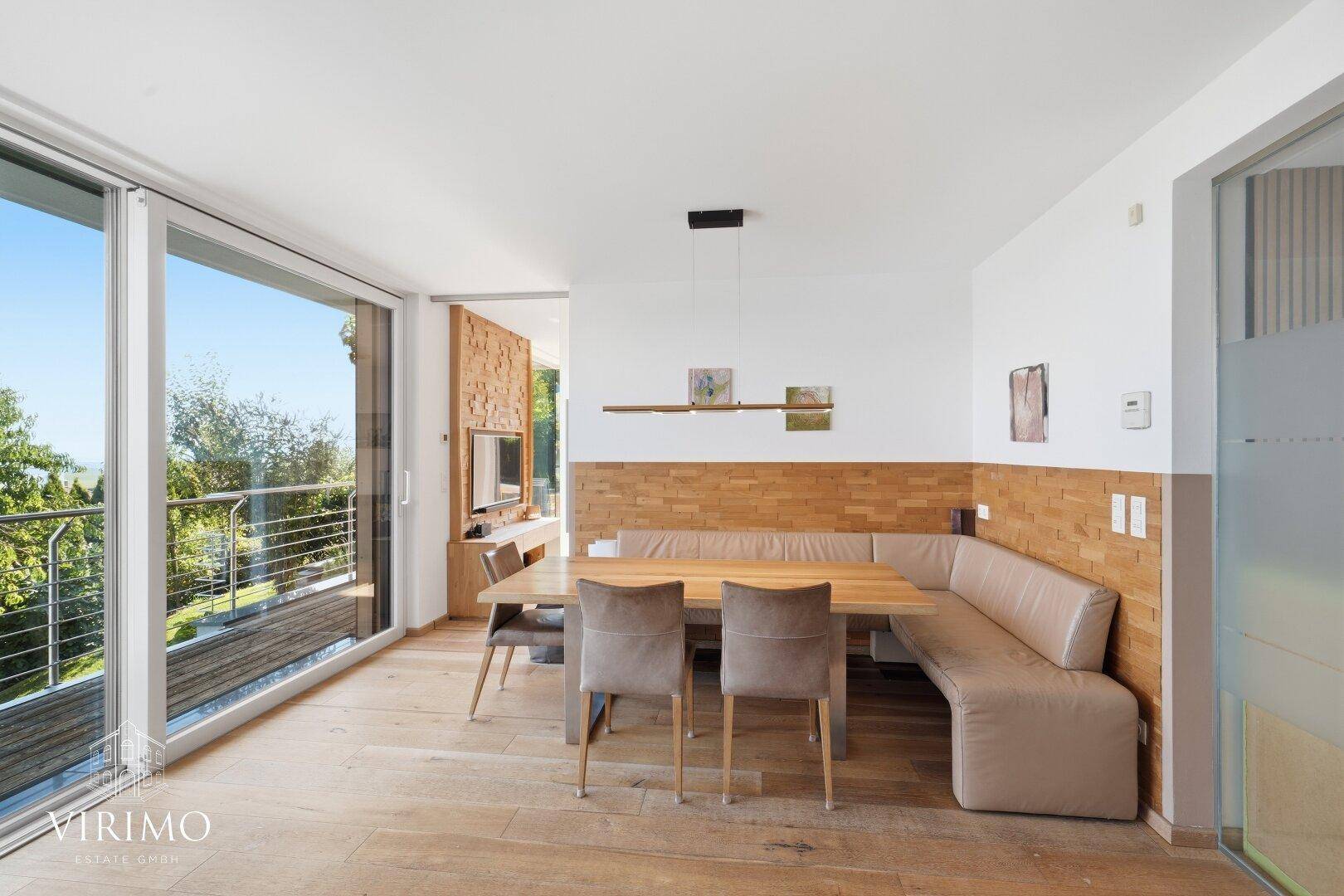 Gemütlicher Essbereich mit Holztisch, Eckbank und Zugang zu einem großen Balkon.