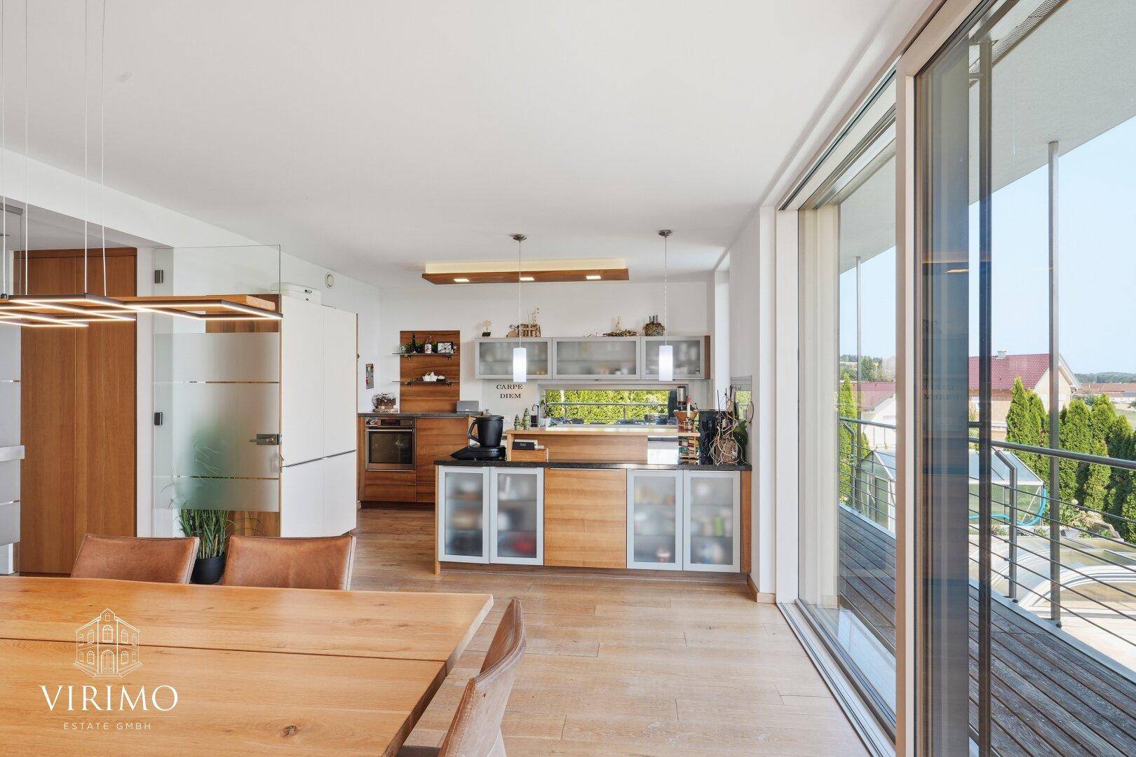 Heller offener Wohn- und Essbereich mit moderner Küche und Zugang zum Balkon.