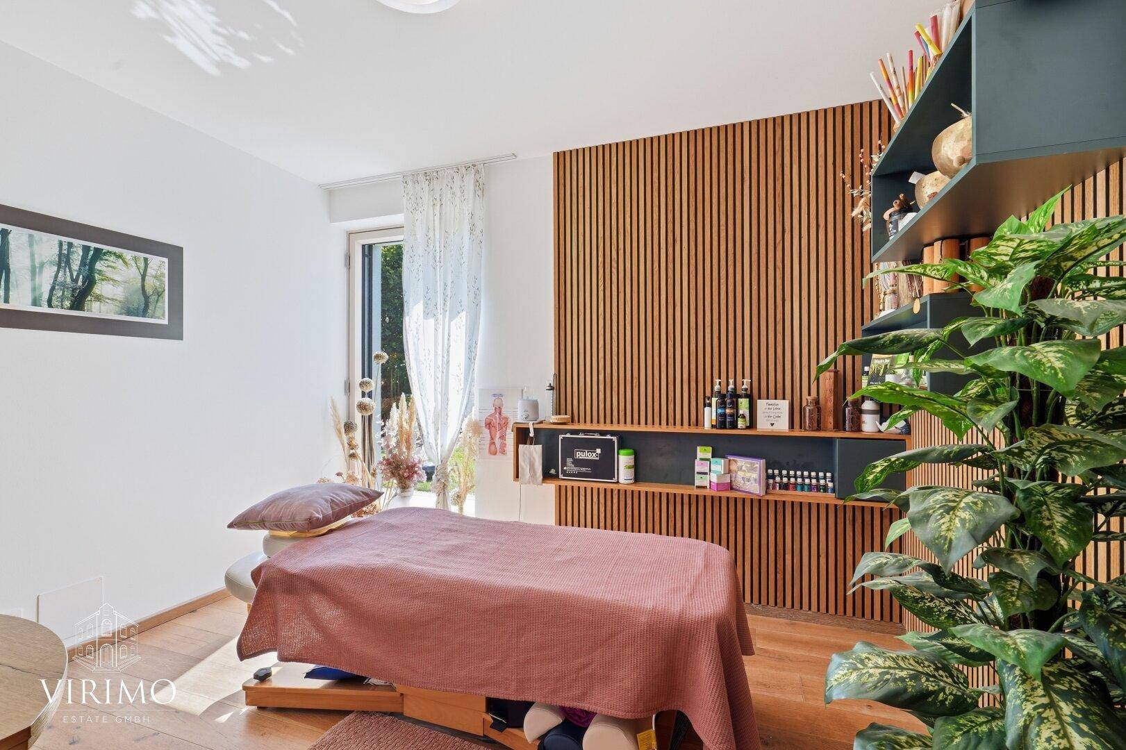 Raum mit Holzwandverkleidung, Massageliege und Pflanzen, ideal als Therapieraum.