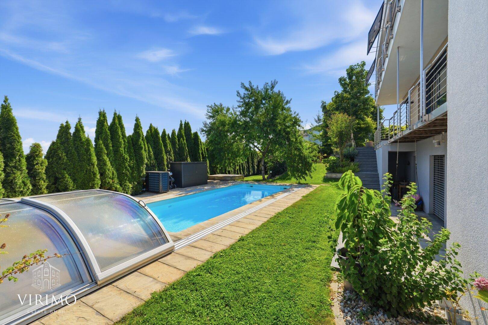 Gepflegter Gartenbereich mit Pool, Rasenfläche und hohen Hecken für Privatsphäre.