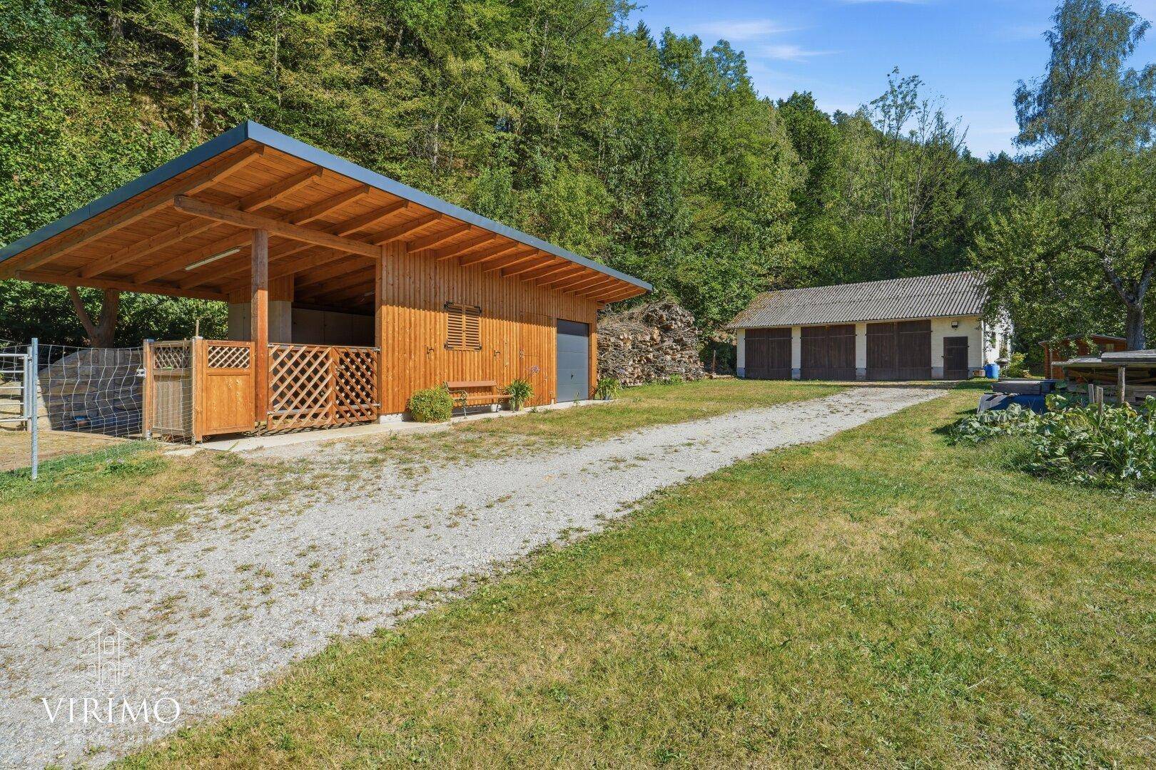 Außenbereich mit Holzschuppen und Garagen, umgeben von viel Grün.