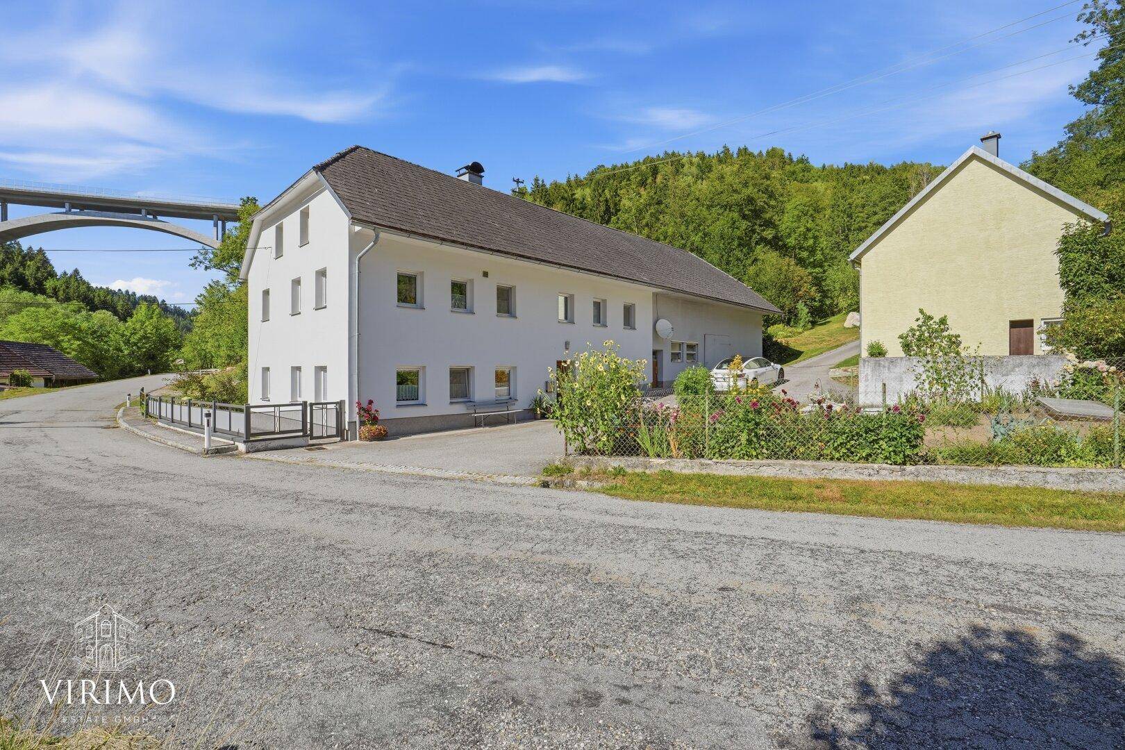Ansicht des Hauptgebäudes von der Straße, umgeben von grüner Landschaft.