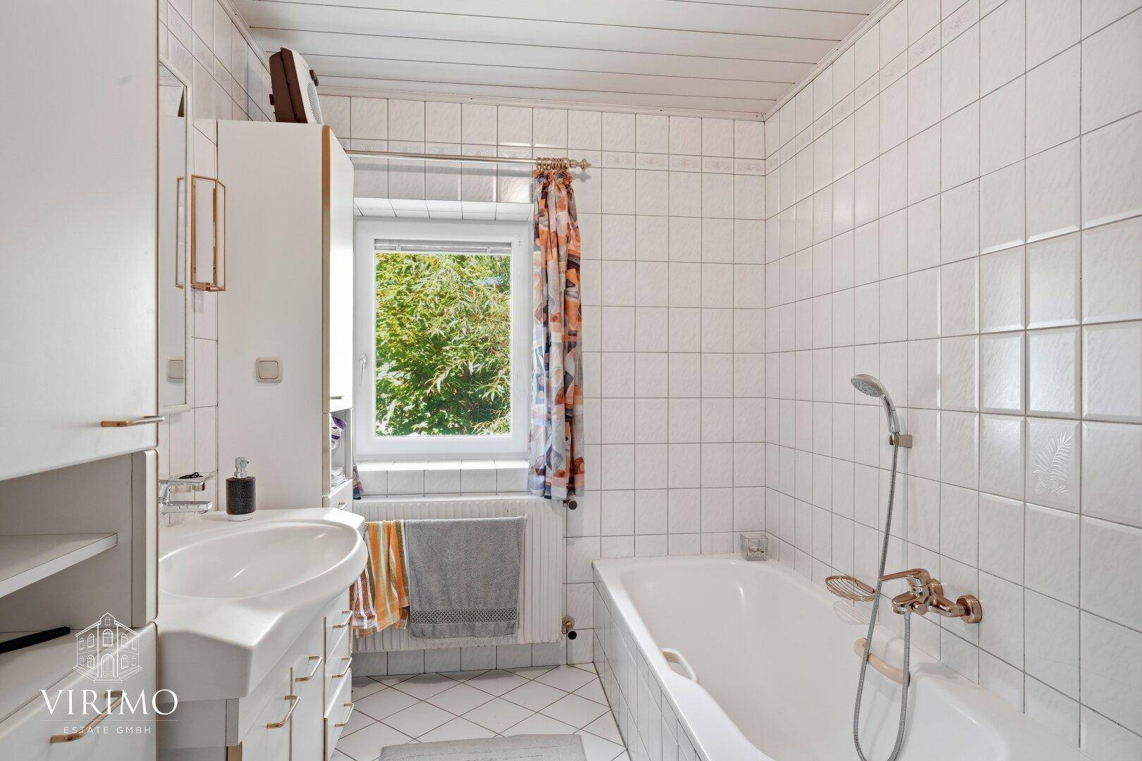 Helles Badezimmer mit weißen Fliesen, Badewanne und Fenster, einfach und funktional.