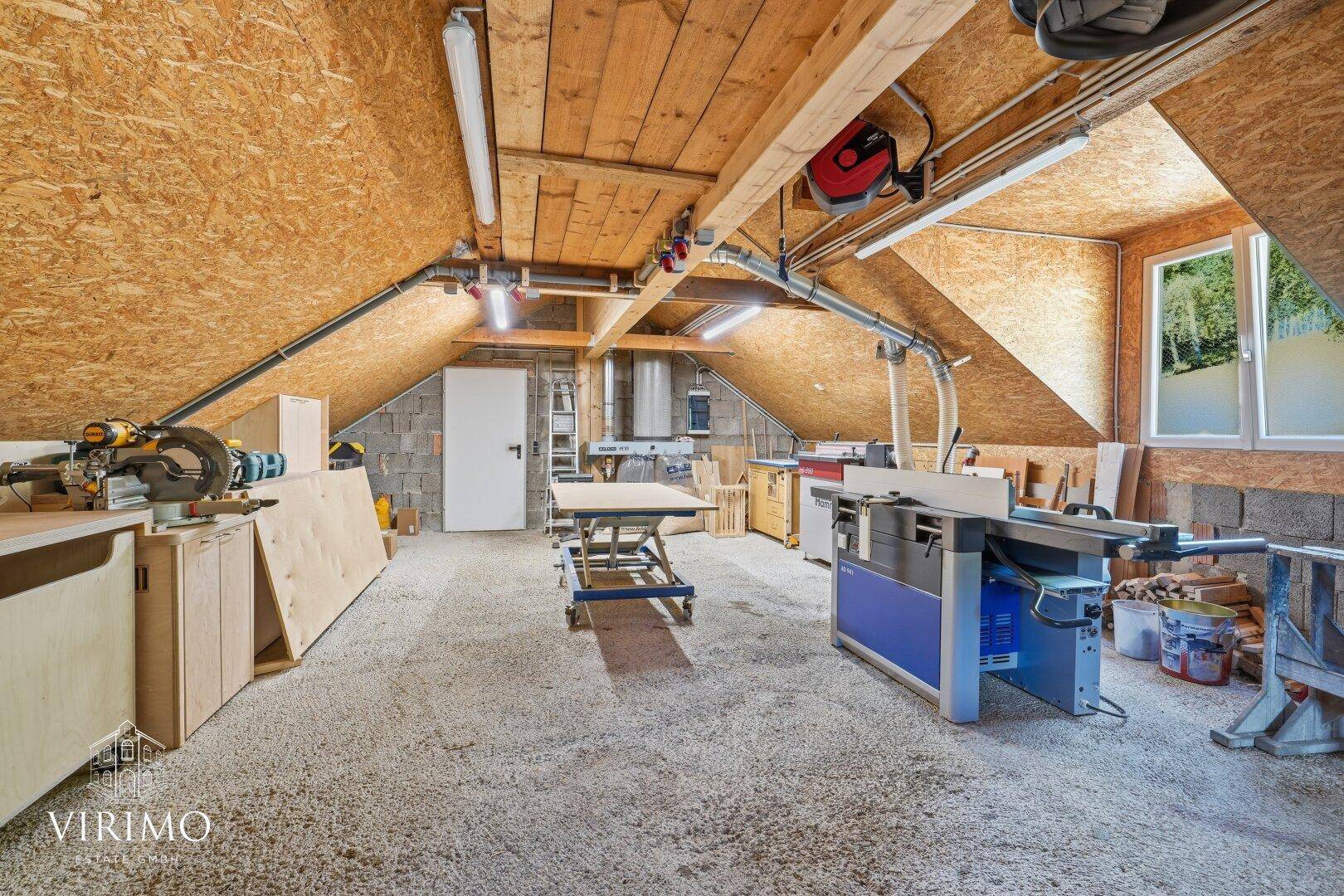 Geräumige Werkstatt im Dachgeschoss mit Holzverkleidung und verschiedenen Maschinen.