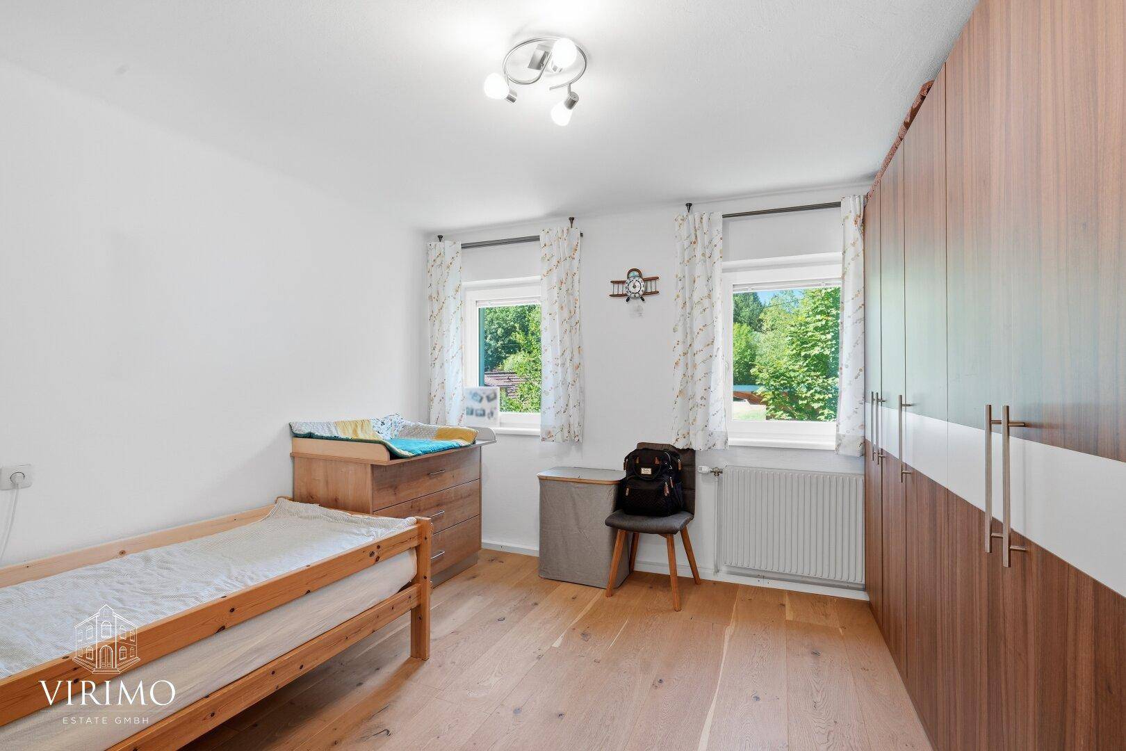 Helles Kinderzimmer mit Einzelbett, großem Kleiderschrank und viel Tageslicht.
