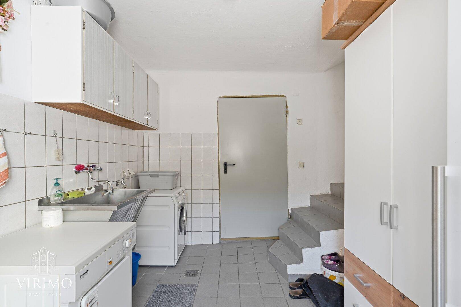 Praktischer Hauswirtschaftsraum mit Waschmaschine, Spülbecken und Stauraum.