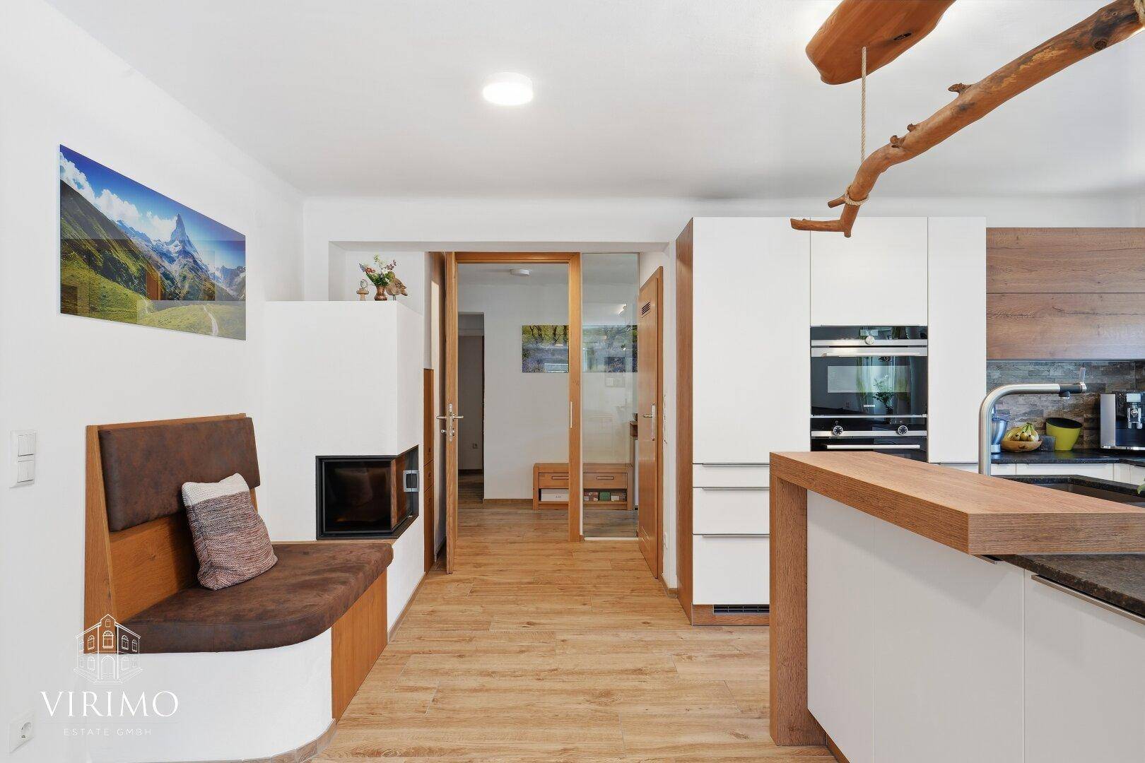 Gemütlicher Küchenbereich mit modernem Kaminofen, integrierter Sitzbank und Holzboden.