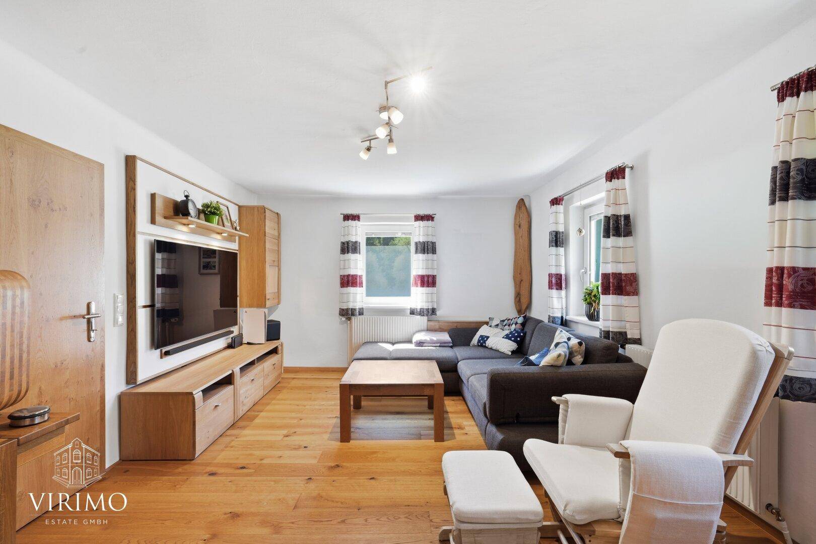 Helles Wohnzimmer mit großem Ecksofa, Holzboden und Medienmöbeln, ideal zum Entspannen.