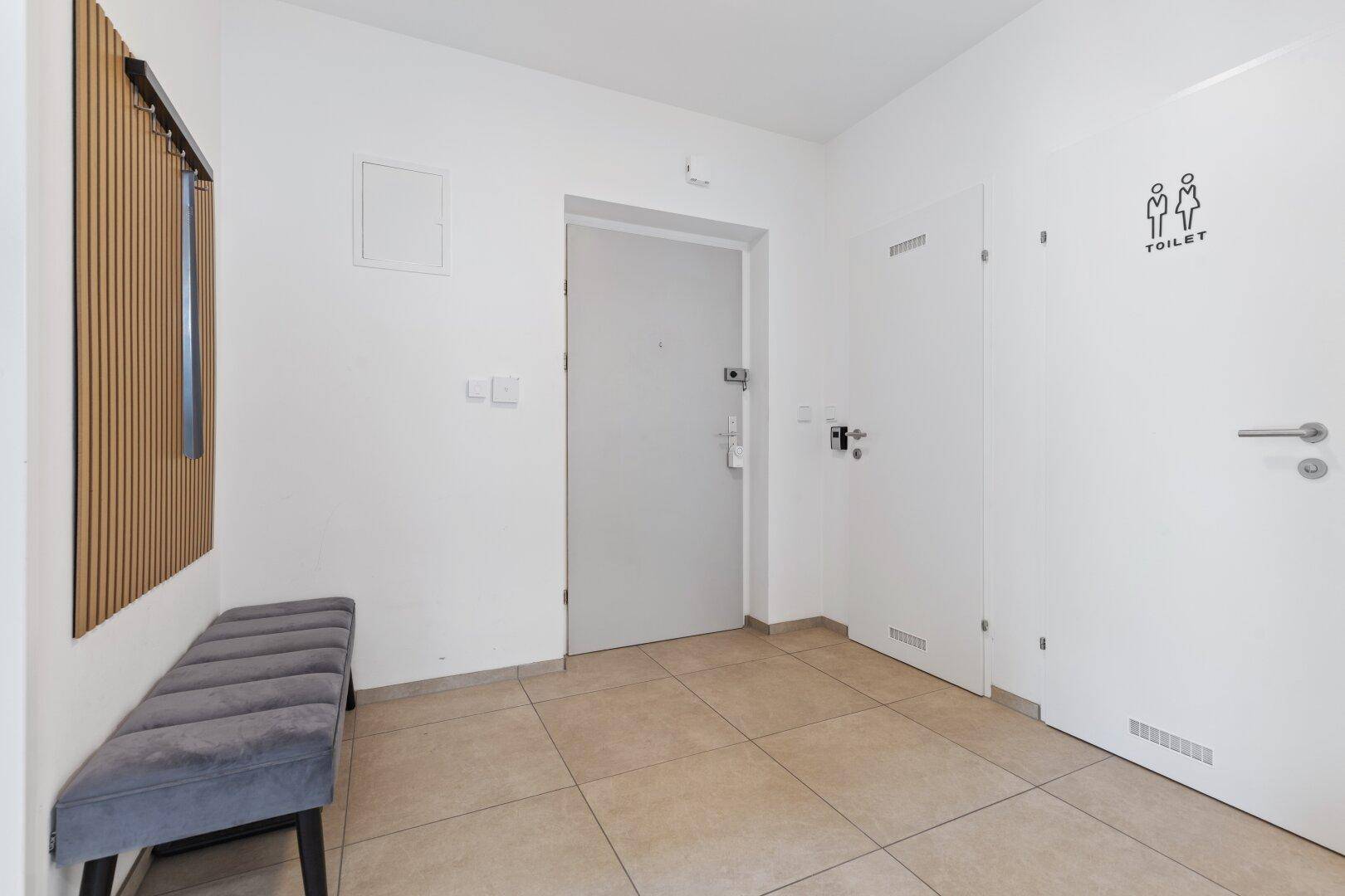 Eingangsbereich mit Fliesenboden und Tür zur separaten Gästetoilette.