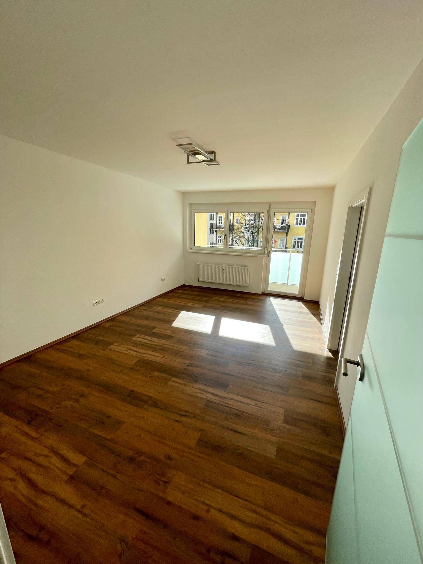 Lichtdurchflutetes Wohnzimmer mit Zugang zum Balkon und Blick auf die Umgebung.