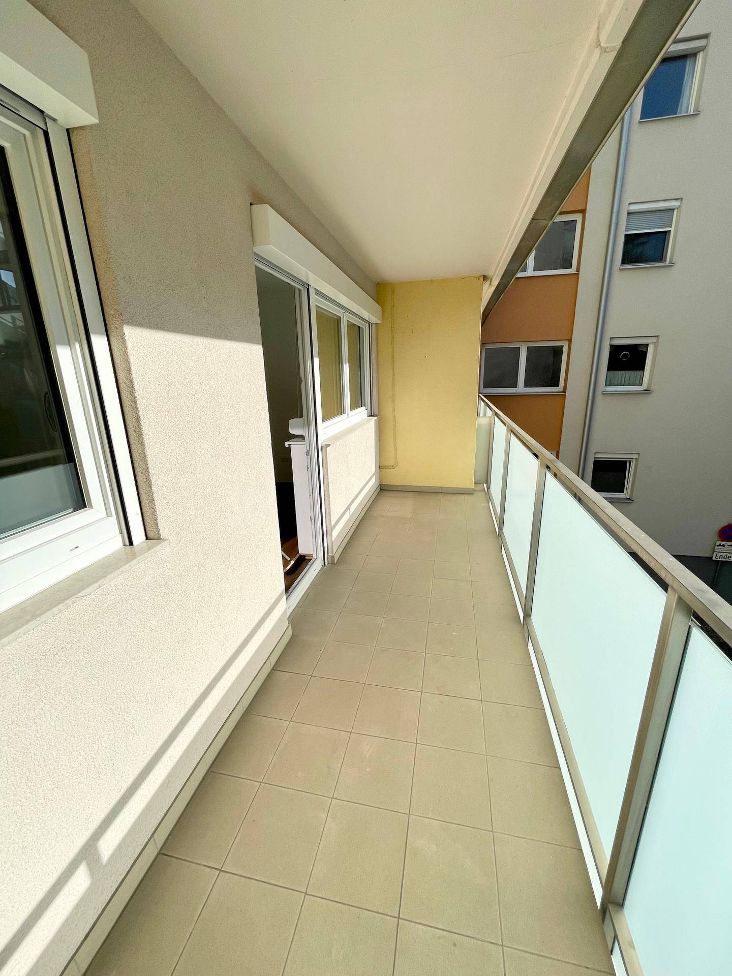 Sonniger Balkon mit Blick auf die umliegenden Gebäude und viel Platz für Pflanzen.