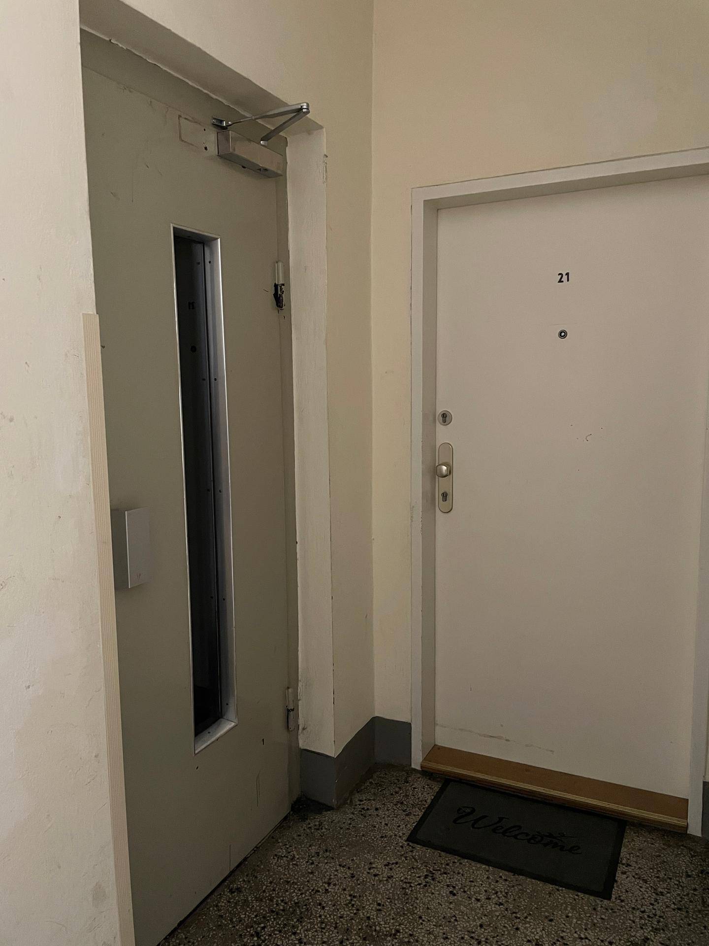 Eingangstür der Wohnung mit Hausnummer 21 und einer Fußmatte im Treppenhaus.