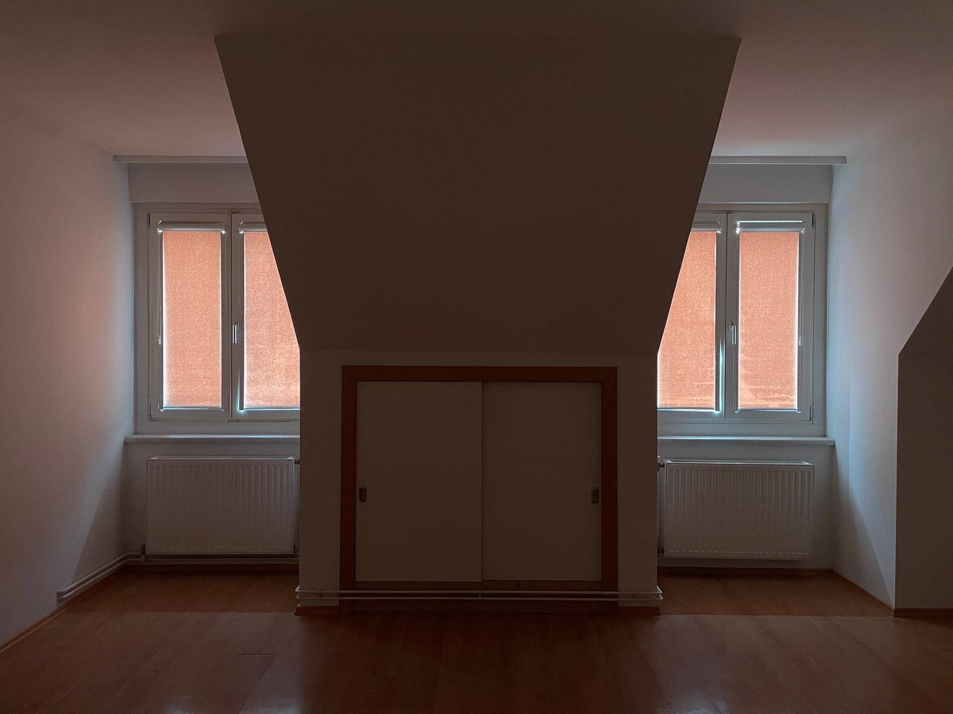 Dachgeschosszimmer mit geschlossenen Rollos an den Fenstern, bietet Privatsphäre und Abdunklung.