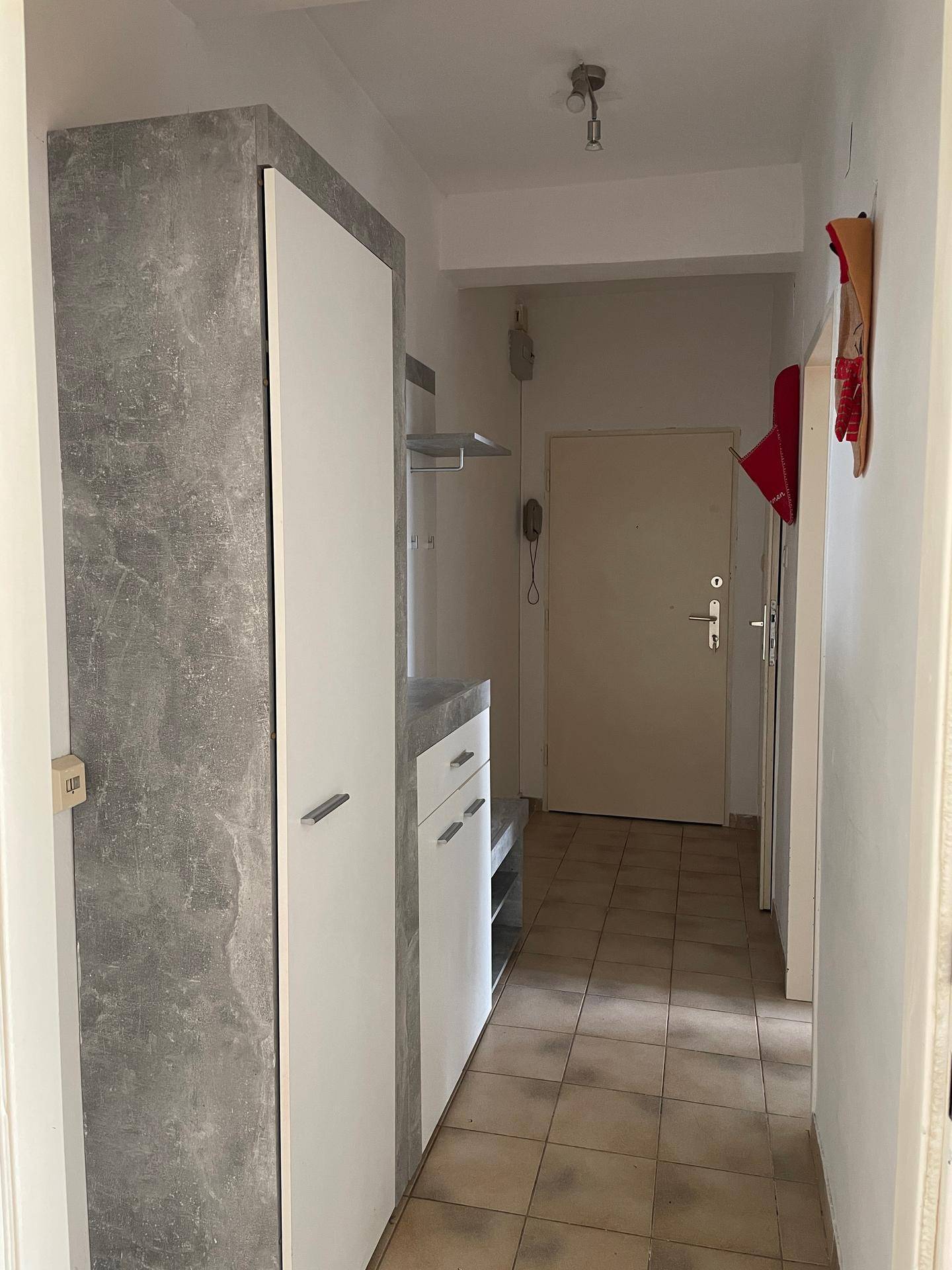 Eingangsbereich mit Fliesenboden und modernem Garderobenschrank in Grau und Weiß.