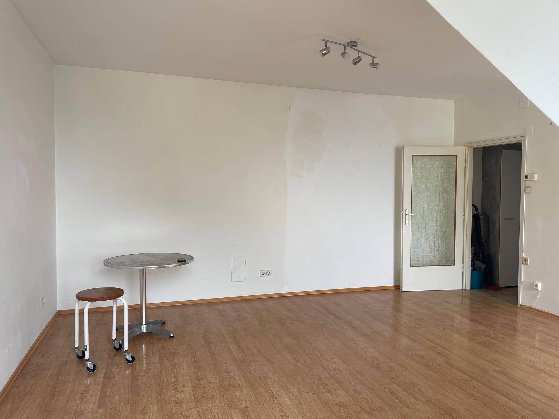 Geräumiges Zimmer mit Holzboden und weiß gestrichenen Wänden, bietet vielseitige Nutzungsmöglichkeiten.