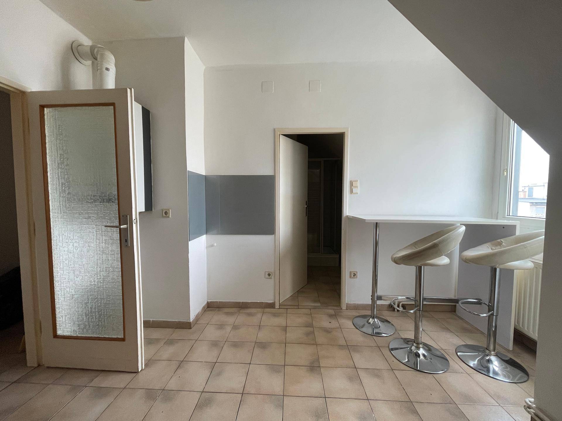Küchenbereich mit Fliesenboden, Bartresen und Hockern, ideal für schnelle Mahlzeiten.