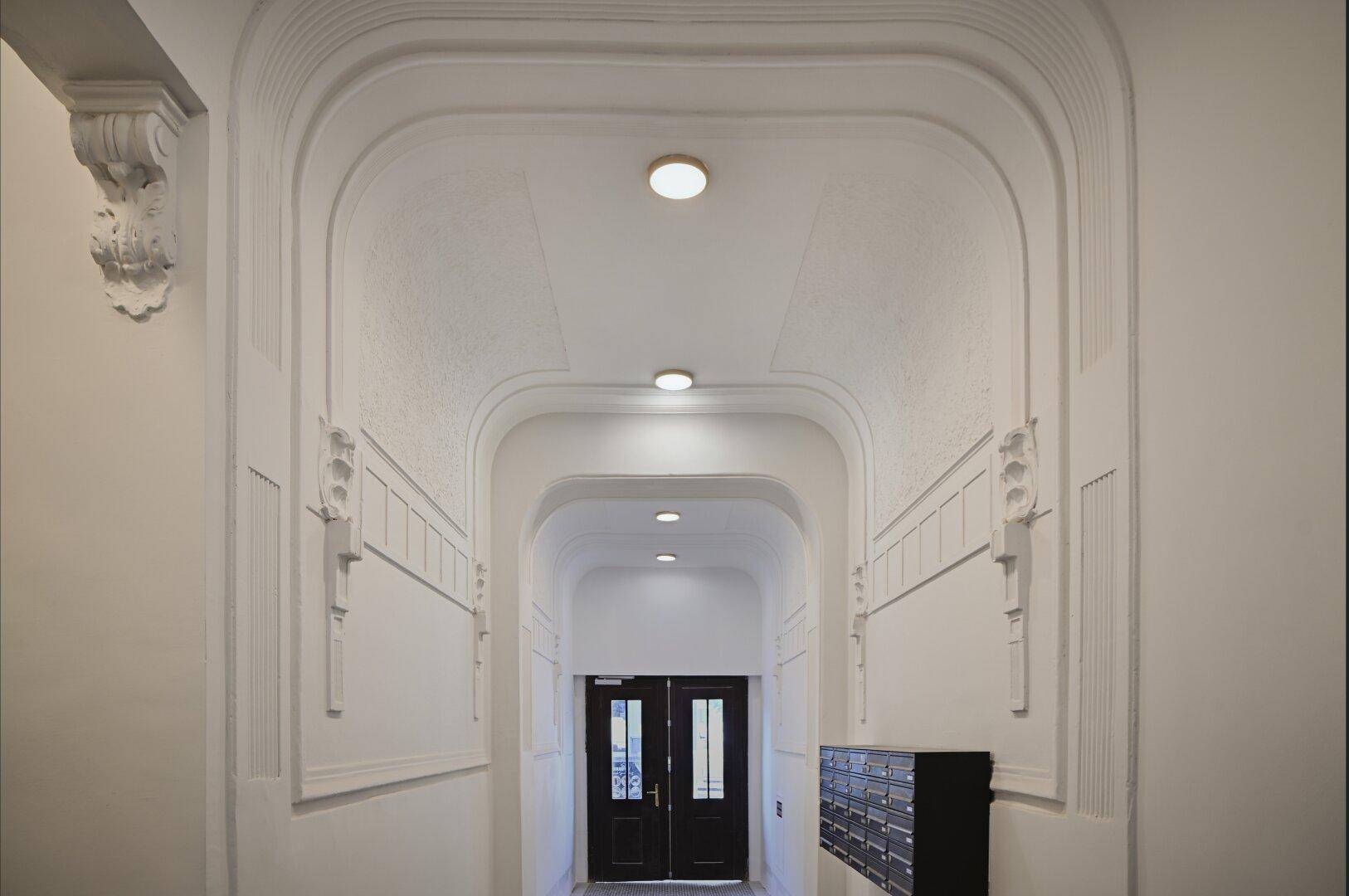 Eleganter Eingangsbereich mit Stuckelementen und Postfächern in einem Altbau.