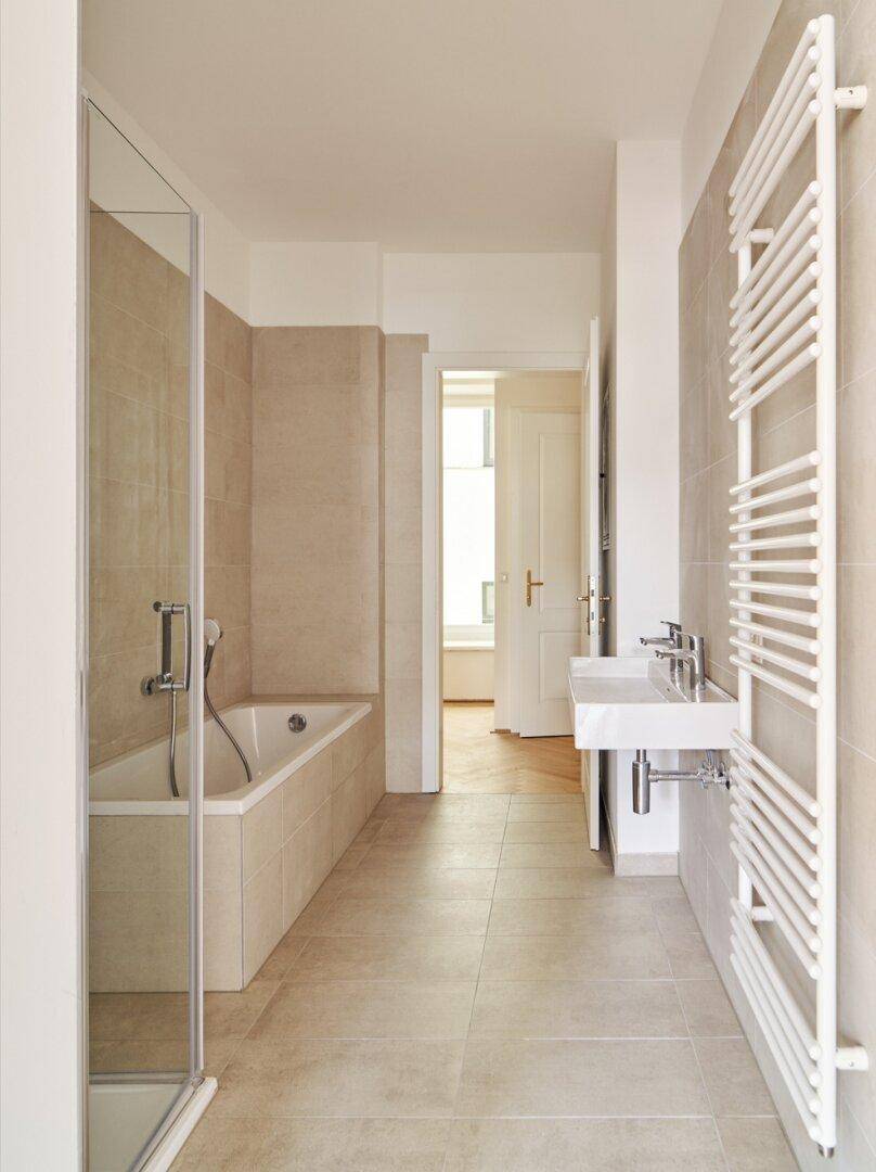 Modernes Badezimmer mit Badewanne, Duschabtrennung, Einzelwaschbecken und Handtuchheizkörper.