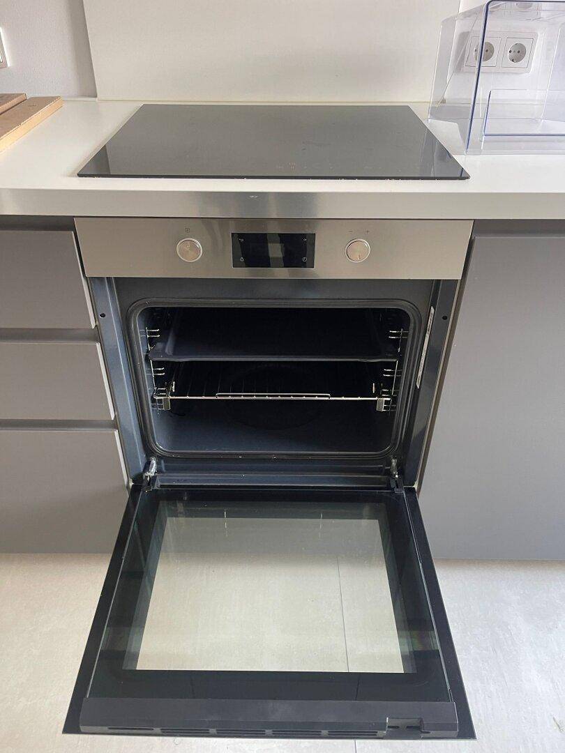 Eingebauter Backofen unter einem Induktionskochfeld in einer modernen Küche.