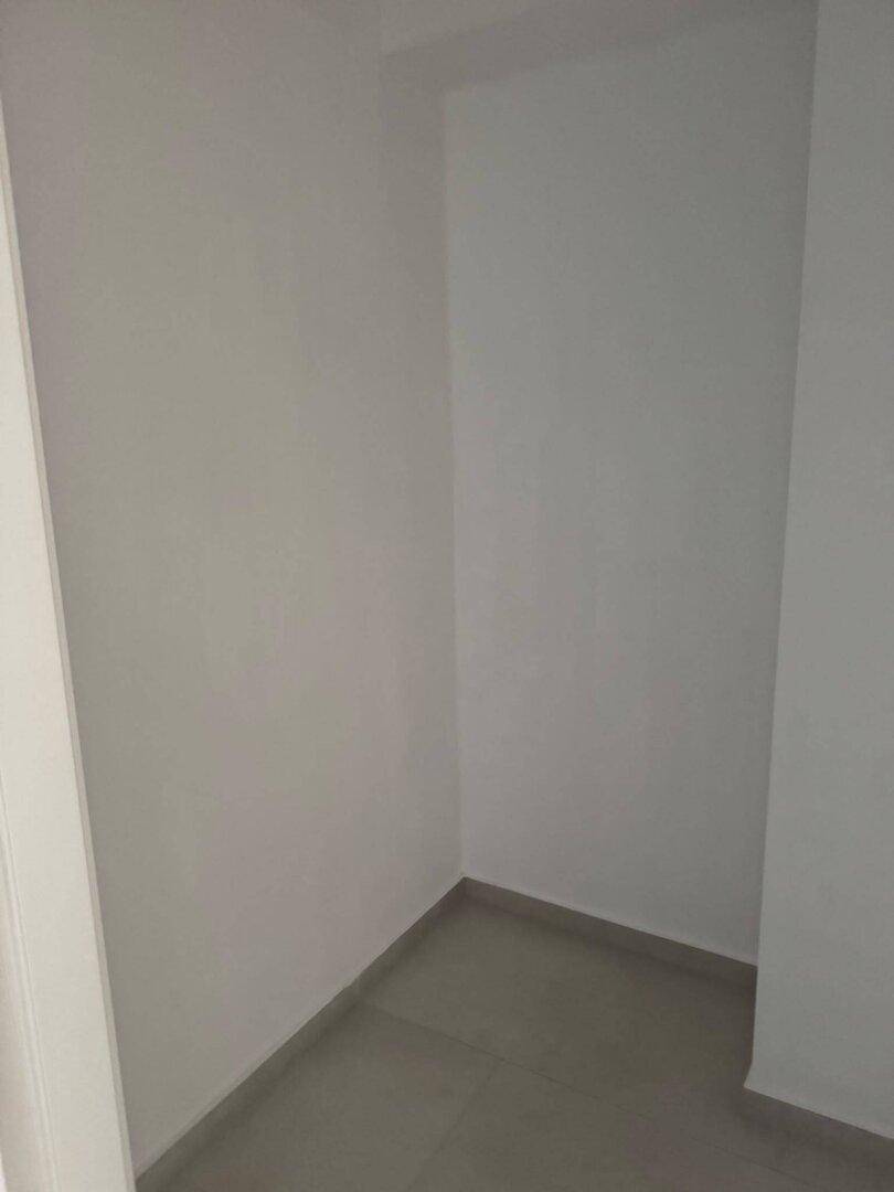 Kleiner, leerer Abstellraum mit gefliestem Boden und weißen Wänden.