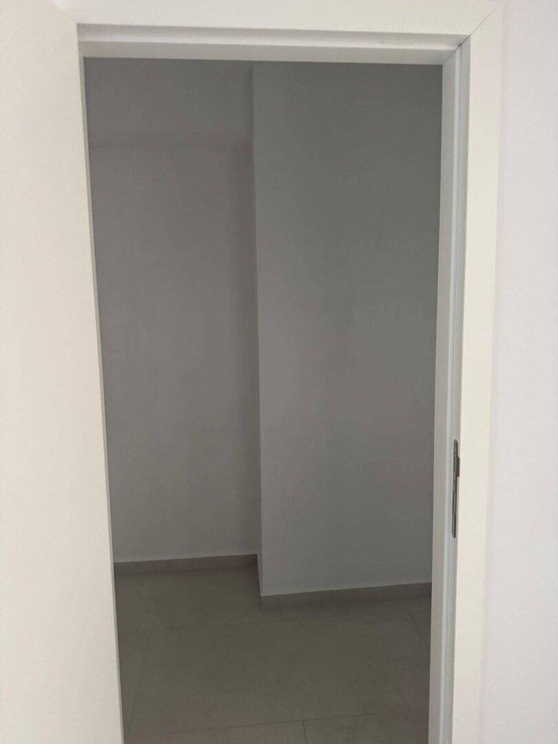 Blick durch eine Tür in einen leeren Raum mit gefliestem Boden.