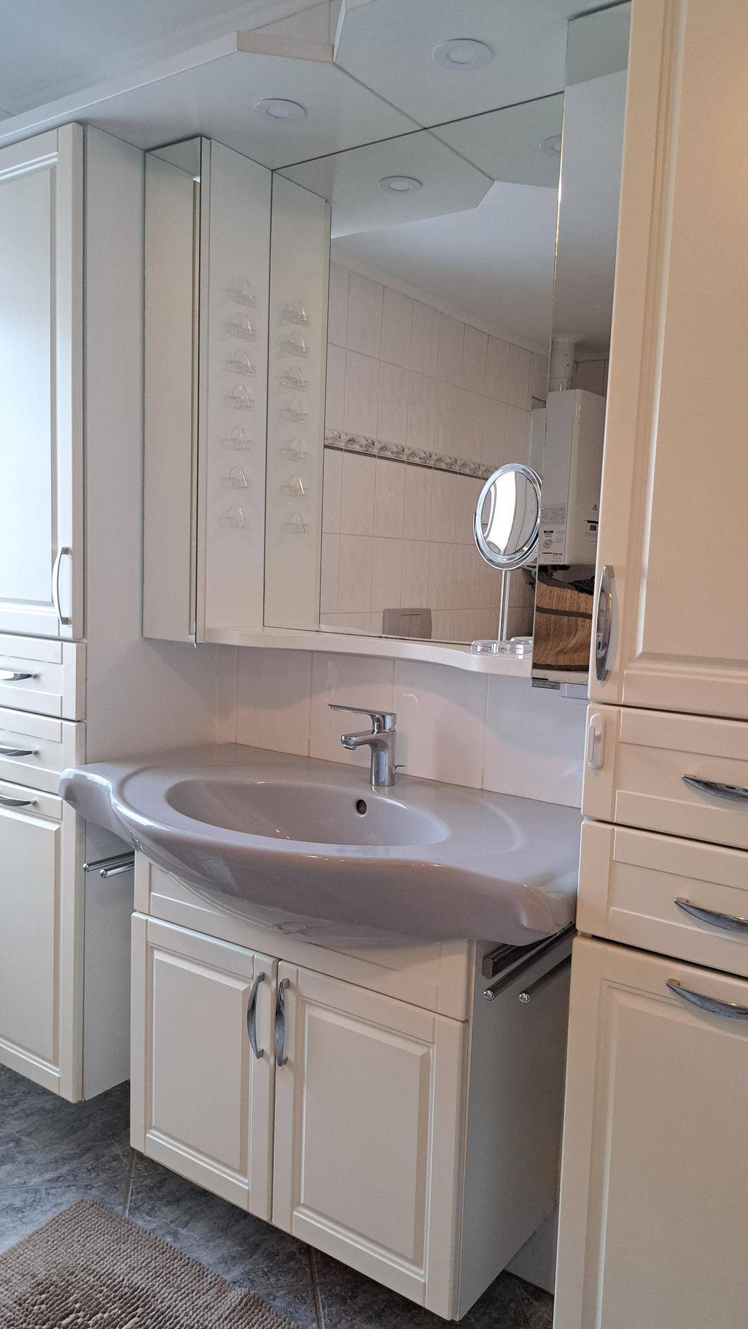 Waschtisch mit integriertem Waschbecken, Spiegelschrank und seitlichen Hochschränken.
