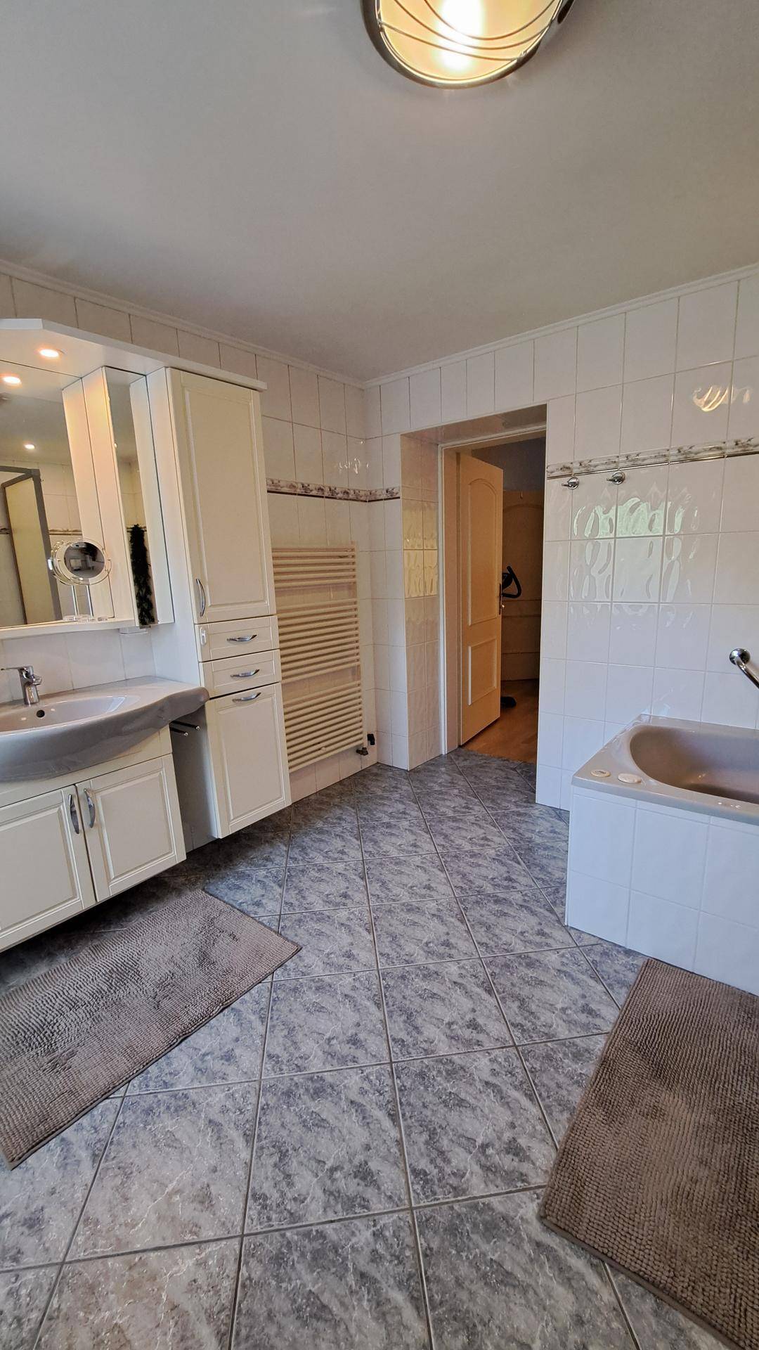 Badezimmer mit Badewanne, Waschtisch und beheiztem Handtuchhalter.