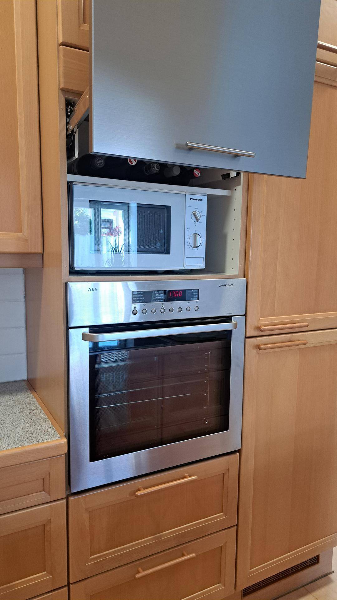 Eingebaute Küchengeräte: Mikrowelle und Backofen in einem modernen Holzschrank.