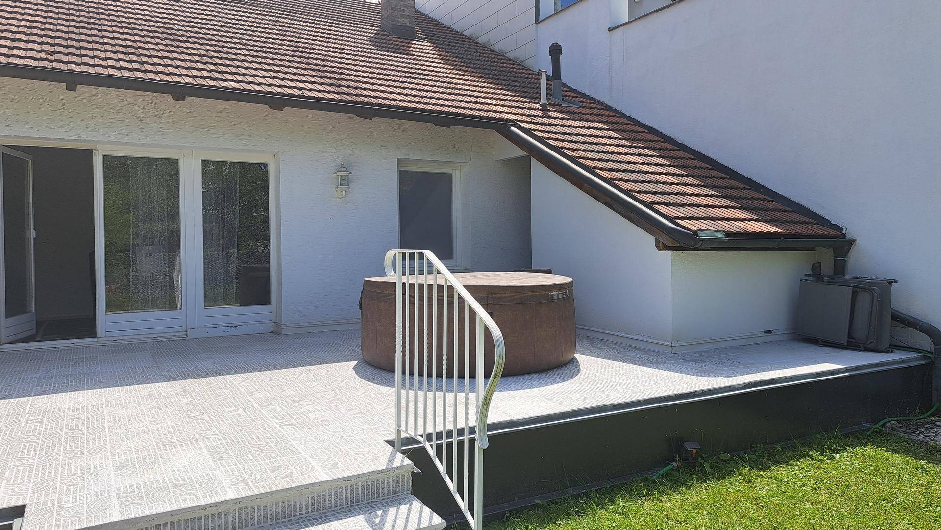 Geräumige Terrasse mit integriertem Whirlpool und Treppe zum Gartenbereich.