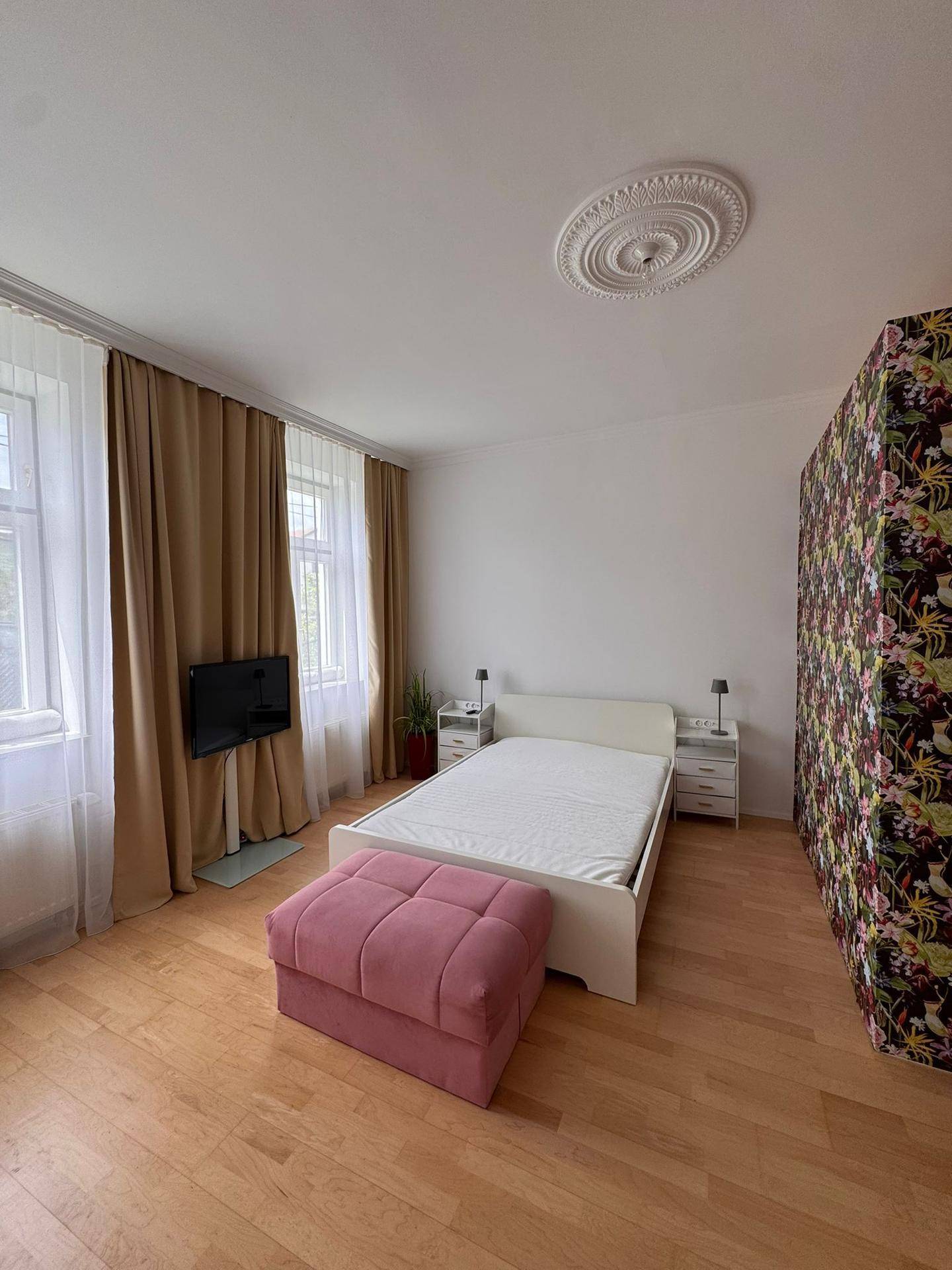 Geräumiges Schlafzimmer mit Doppelbett, Nachttischen und zwei großen Fenstern.