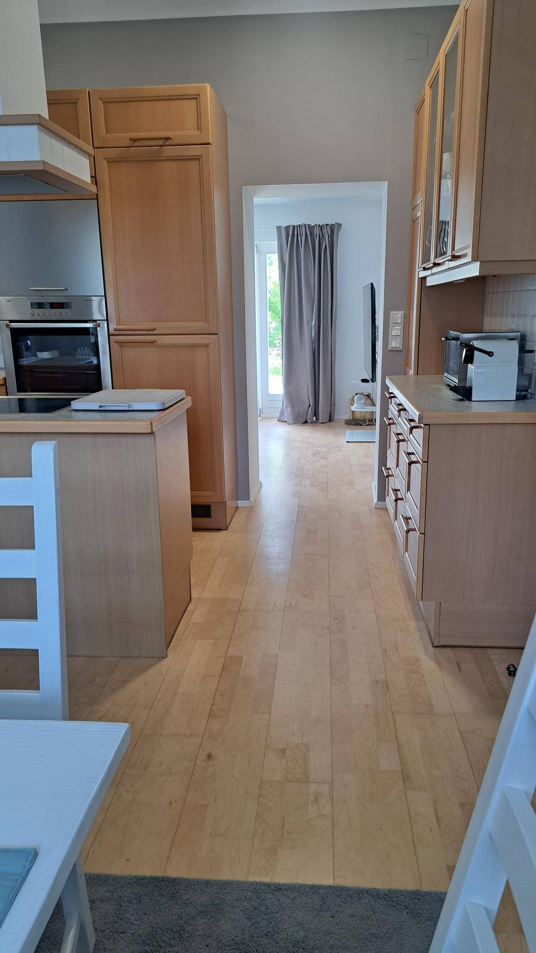 Offener Küchenbereich mit Holzfußboden, der zu einem weiteren Raum führt.