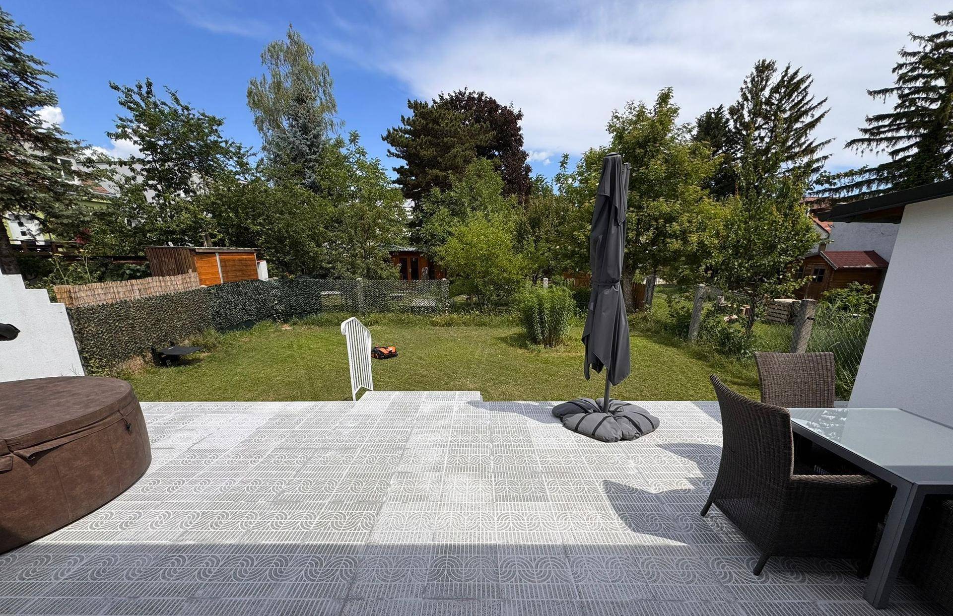 Große Terrasse mit Gartenblick, Outdoor-Möbeln, Sonnenschirm und einem Whirlpool.