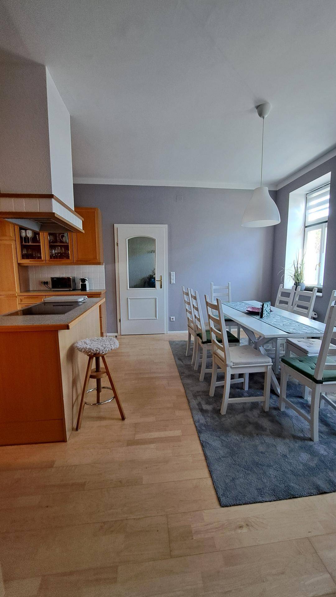 Offene Küche mit Holzelementen und Essbereich mit großem Esstisch und Holzfußboden.
