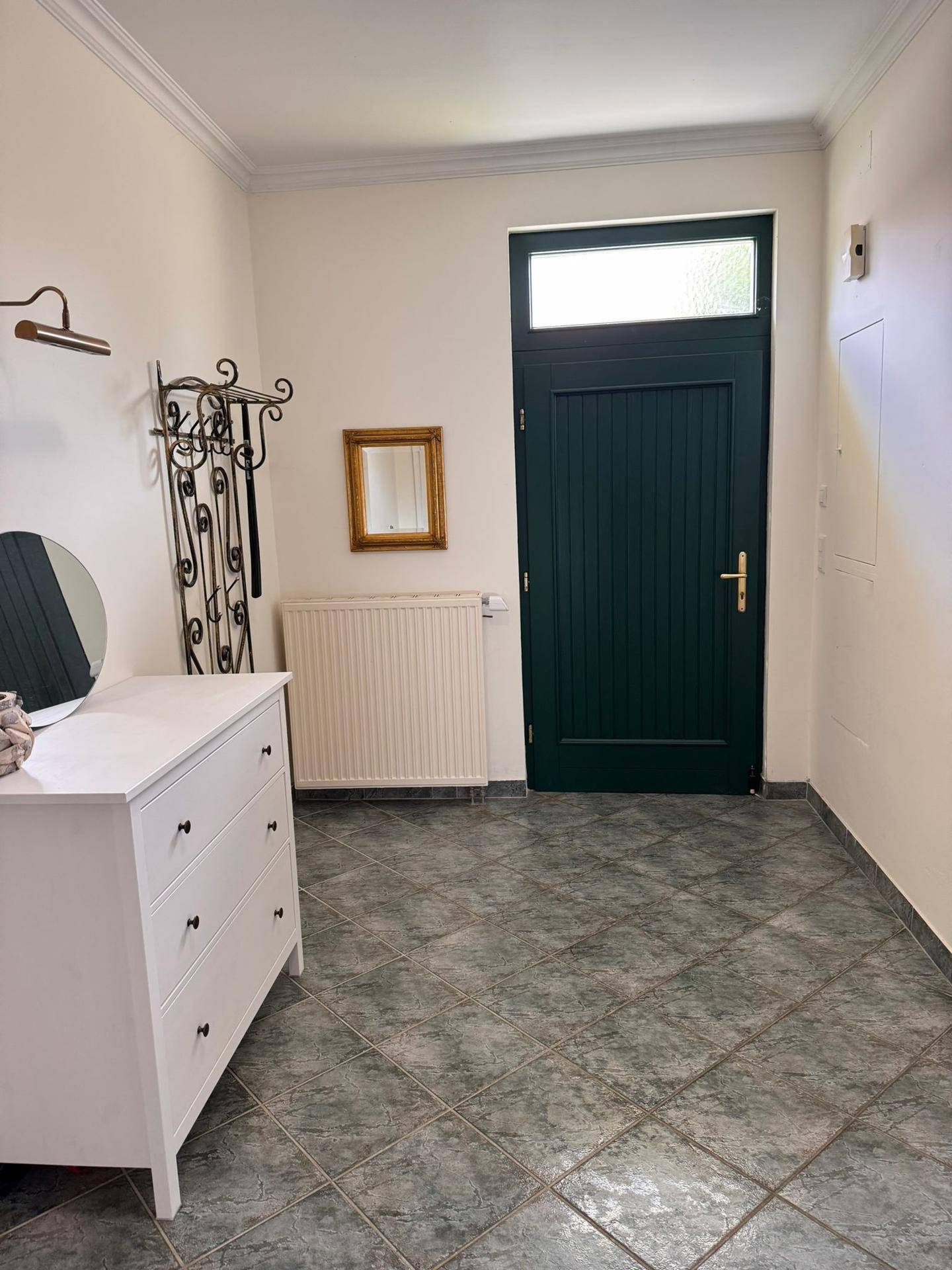 Eingangsbereich mit Fliesenboden, weißer Kommode und Garderobe, gut beleuchtet.