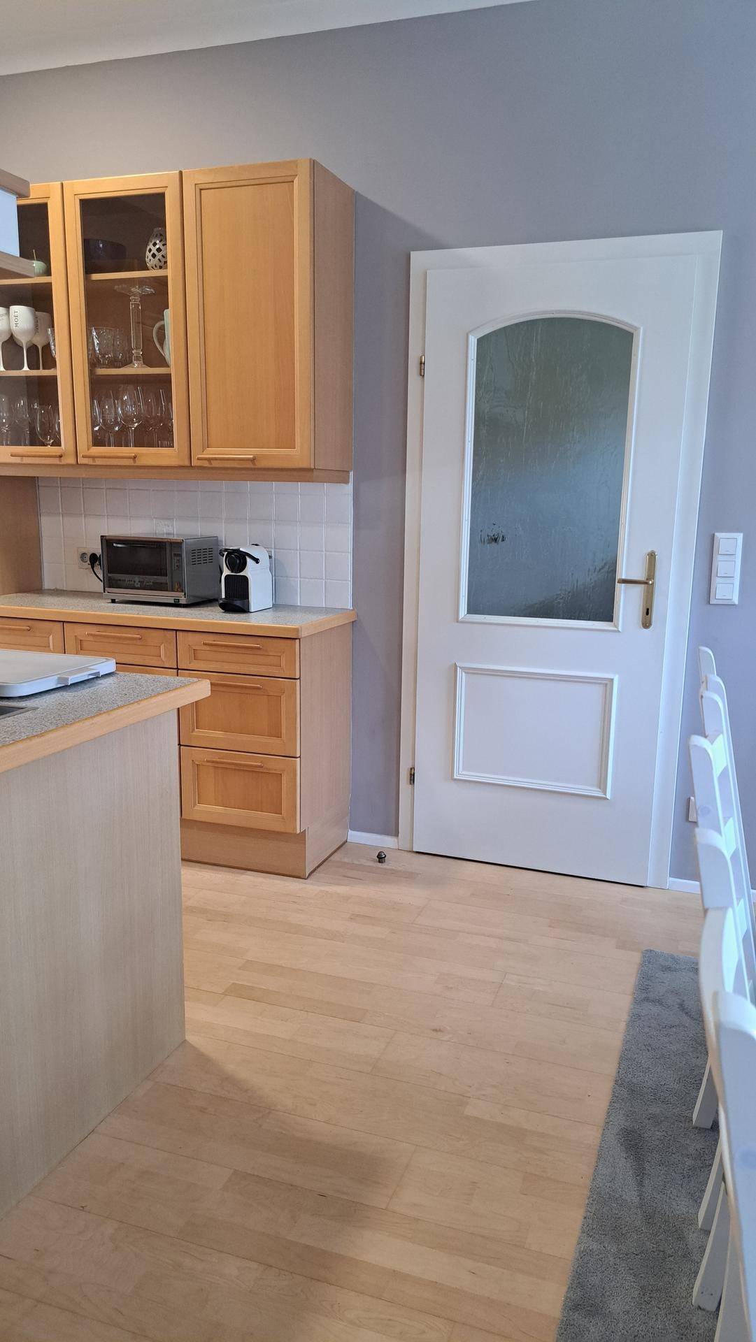 Offene Küche mit Holzelementen und Essbereich, getrennt durch eine weiße Tür.