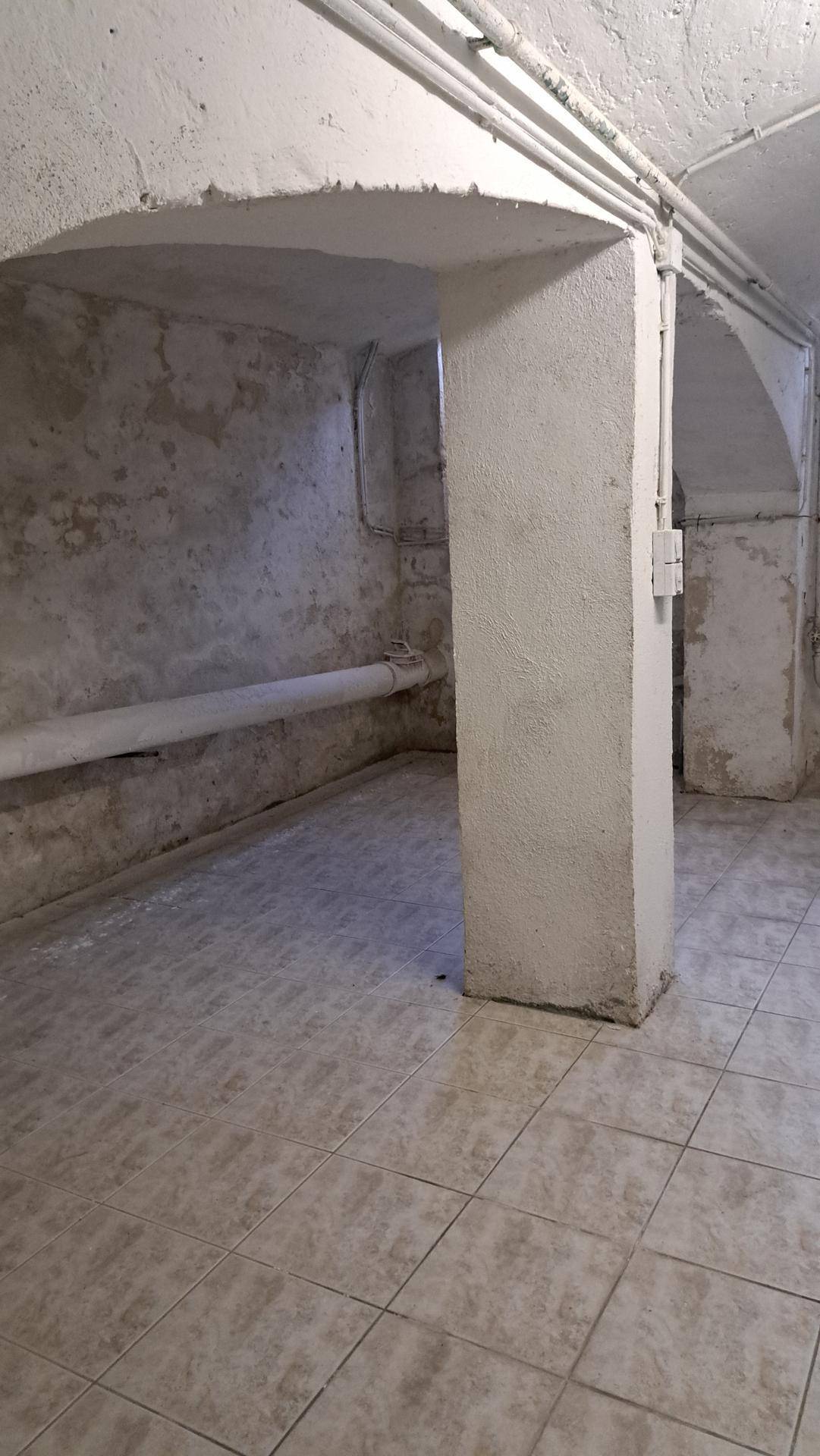 Geräumiger Kellerraum mit Betonwänden und gefliestem Boden.