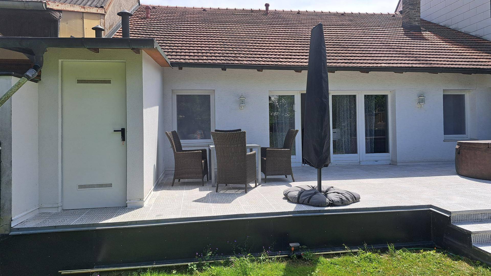 Terrasse mit Gartenmöbeln und Sonnenschirm, direkt am Haus gelegen mit Zugang zum Garten.