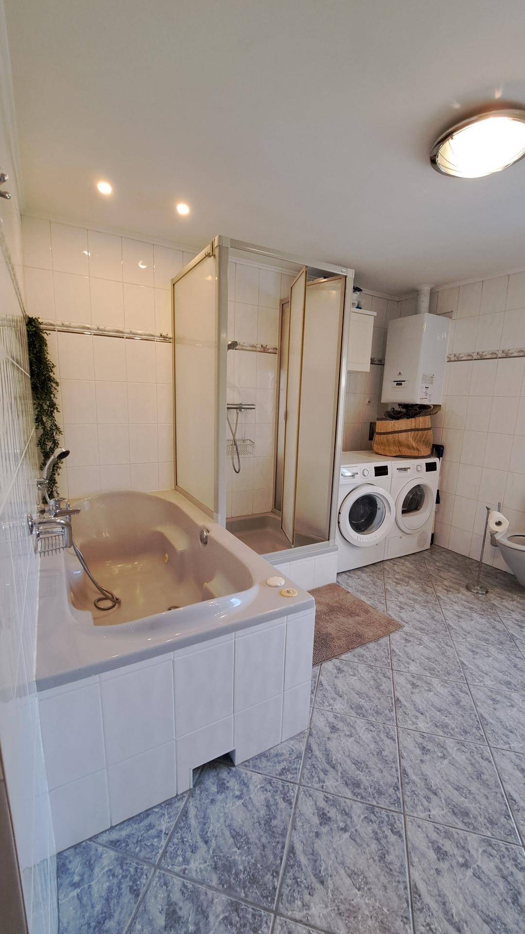 Badezimmer mit Badewanne, Duschkabine, Waschmaschine und Trockner.