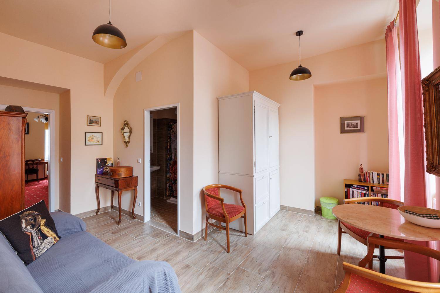 Heller Wohnbereich mit Essplatz, Sofa, weißem Schrank und großen Fenstern.