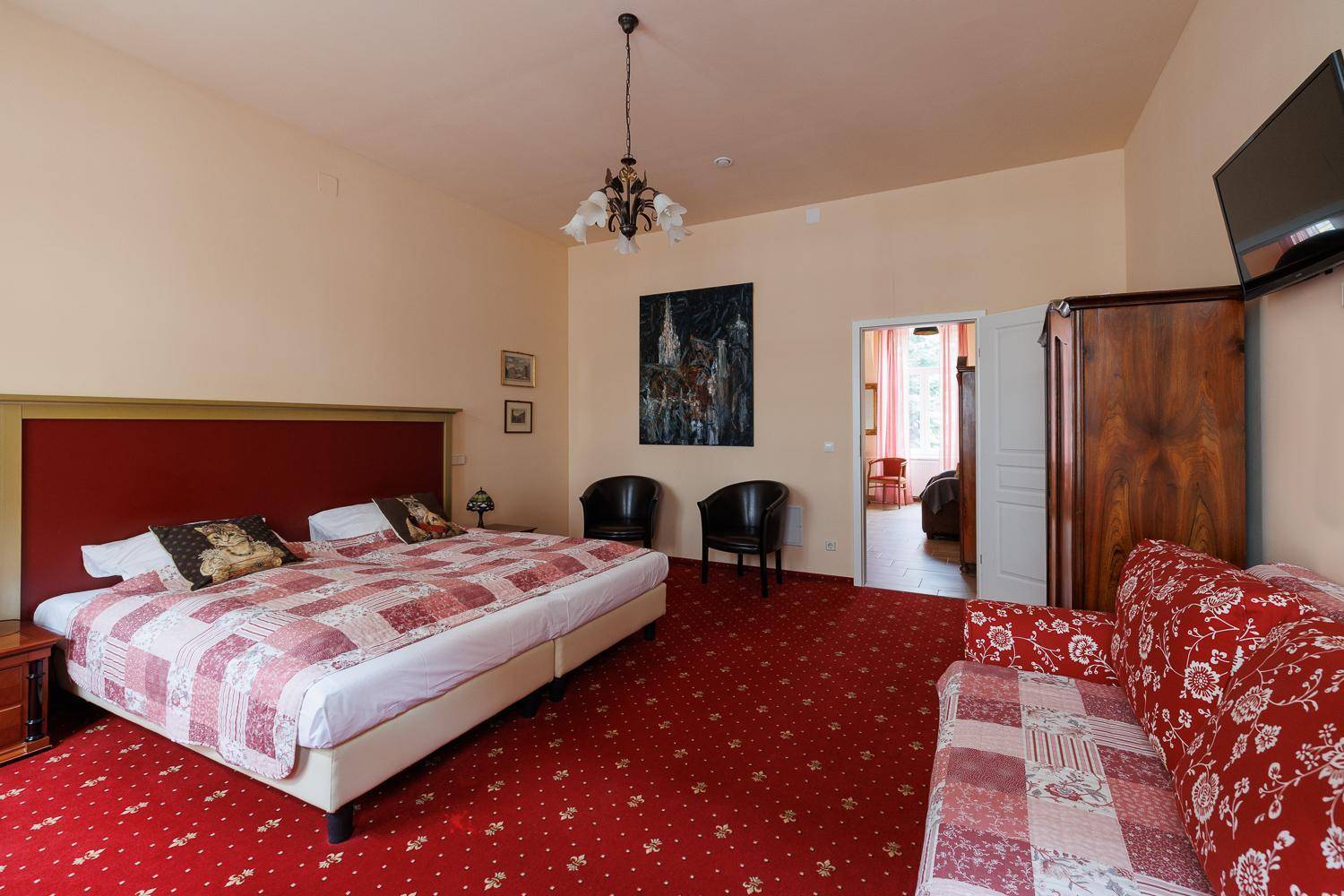 Geräumiges Schlafzimmer mit rotem Teppichboden, großem Bett und einem bequemen Sofa.