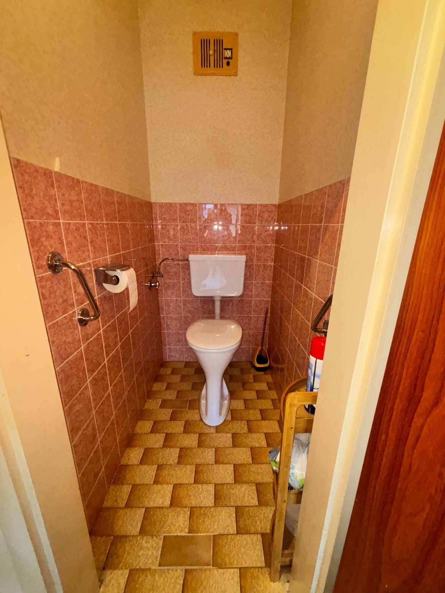 Separates WC mit Toilette und rosa Fliesen, funktional und gut erhalten.