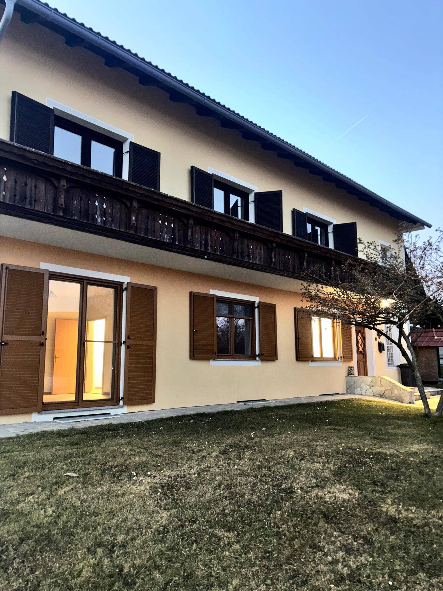 Seitenansicht des Hauses mit Garten, Balkon und traditionellen Fensterläden.